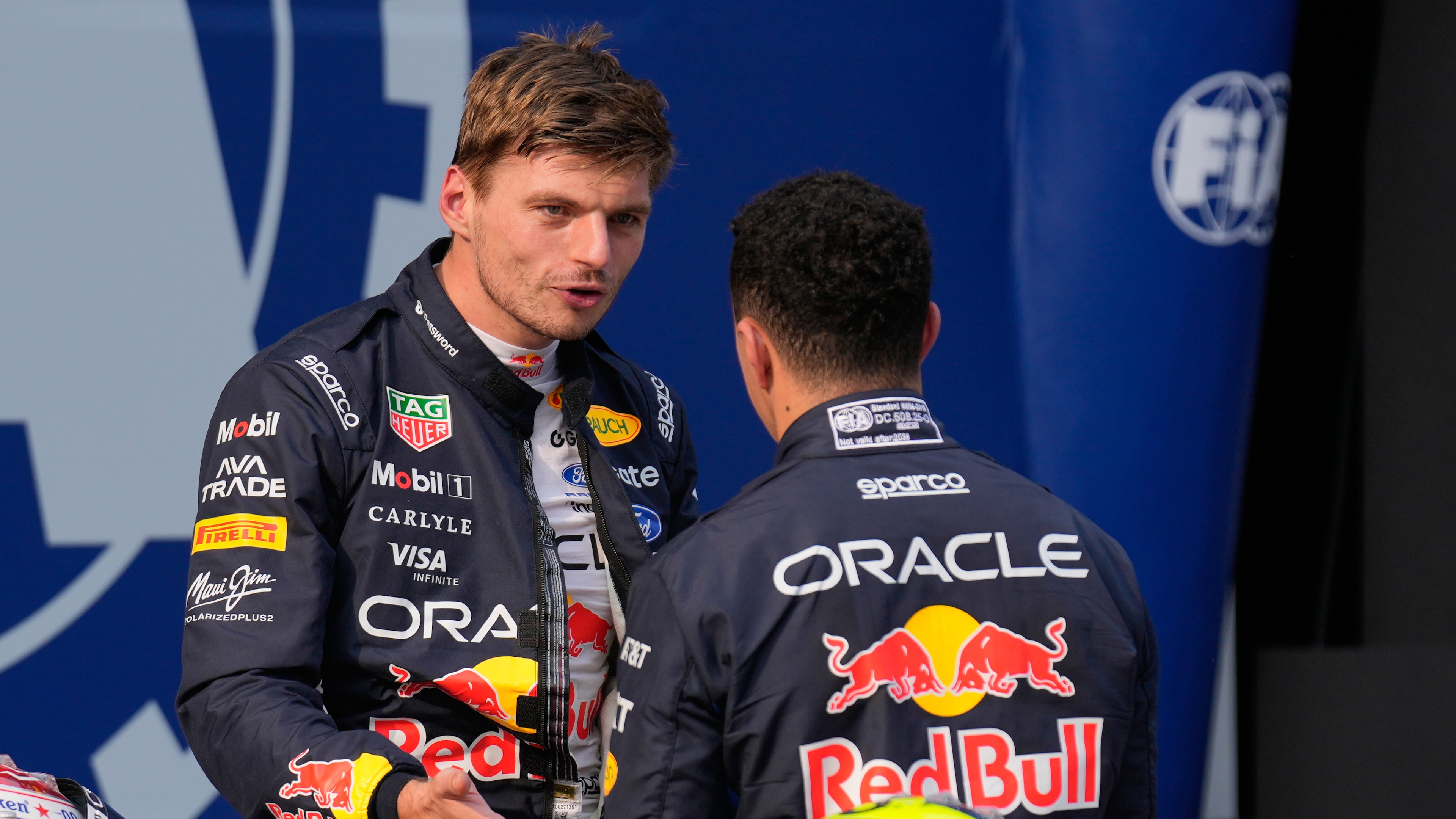 Red Bull driver Max Verstappen of the Netherlands, pole position, talks with his teammate Isack Hadjar of France, third fastest time after the qualifying session ahead of the Bahrain Grand Prix in Sepang, Malaysia, Saturday, Oct. 3, 2026. (AP Photo/Aijaz Rahi)