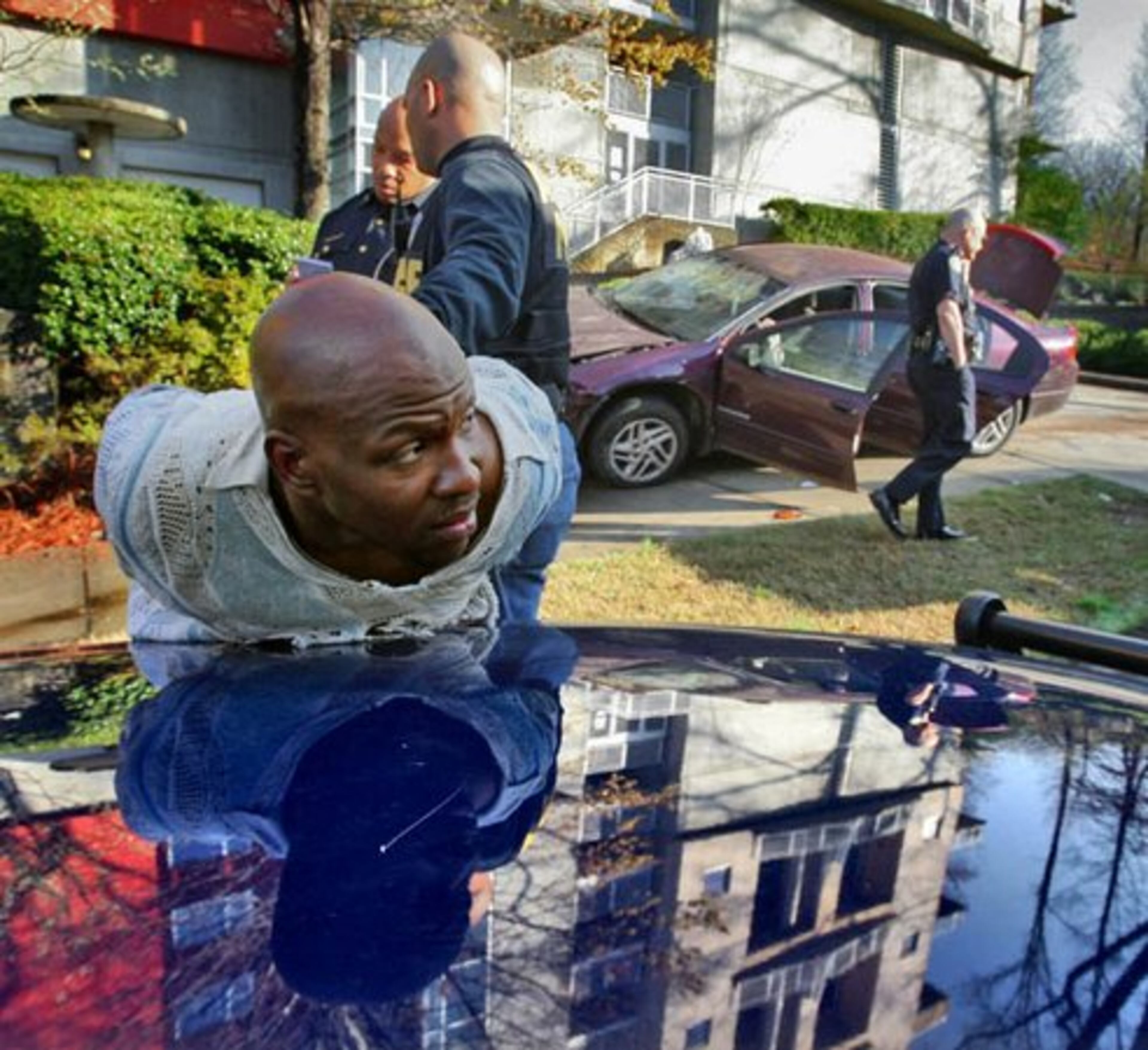A suspect is handcuffed and placed on the hood of an Atlanta police cruiser after police apprehended two suspects following a chase that ended when the suspects crashed their car into the stone entryway of the Copenhill Lofts on Ralph McGill Boulevard. The suspects struck a Nissan Altima before smashing into the lofts where actress Jane Fonda lives.