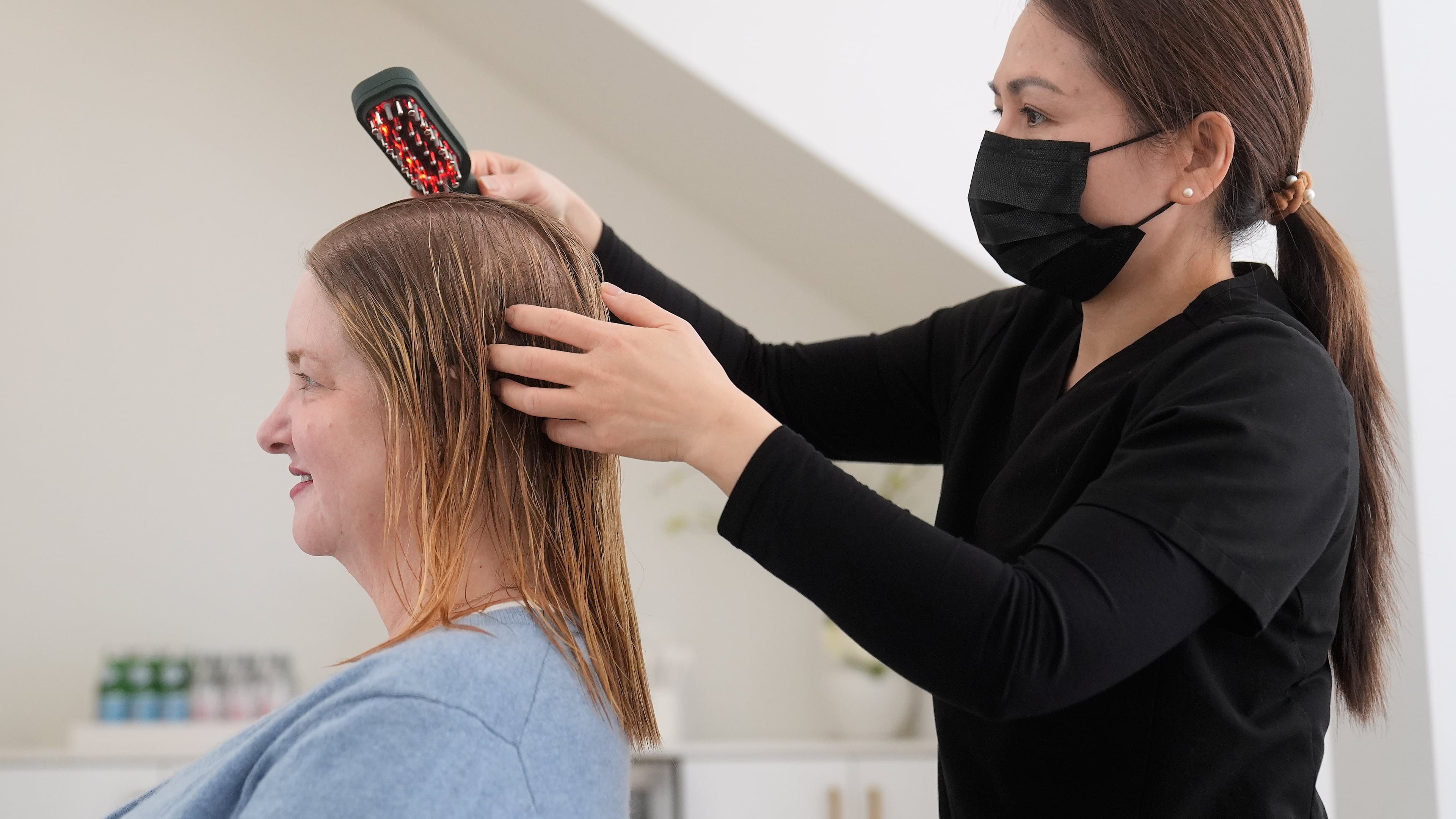 Head spa specialist Ha Truong, right, uses a Red and Blue light brush on Liz Evans to help with hair growth and reduce bacteria while massaging the scalp to help the scalp serum absorb during a treatment at Sunday Headspa Thursday, April 16, 2026, in San Francisco. (AP Photo/Jeff Chiu)
