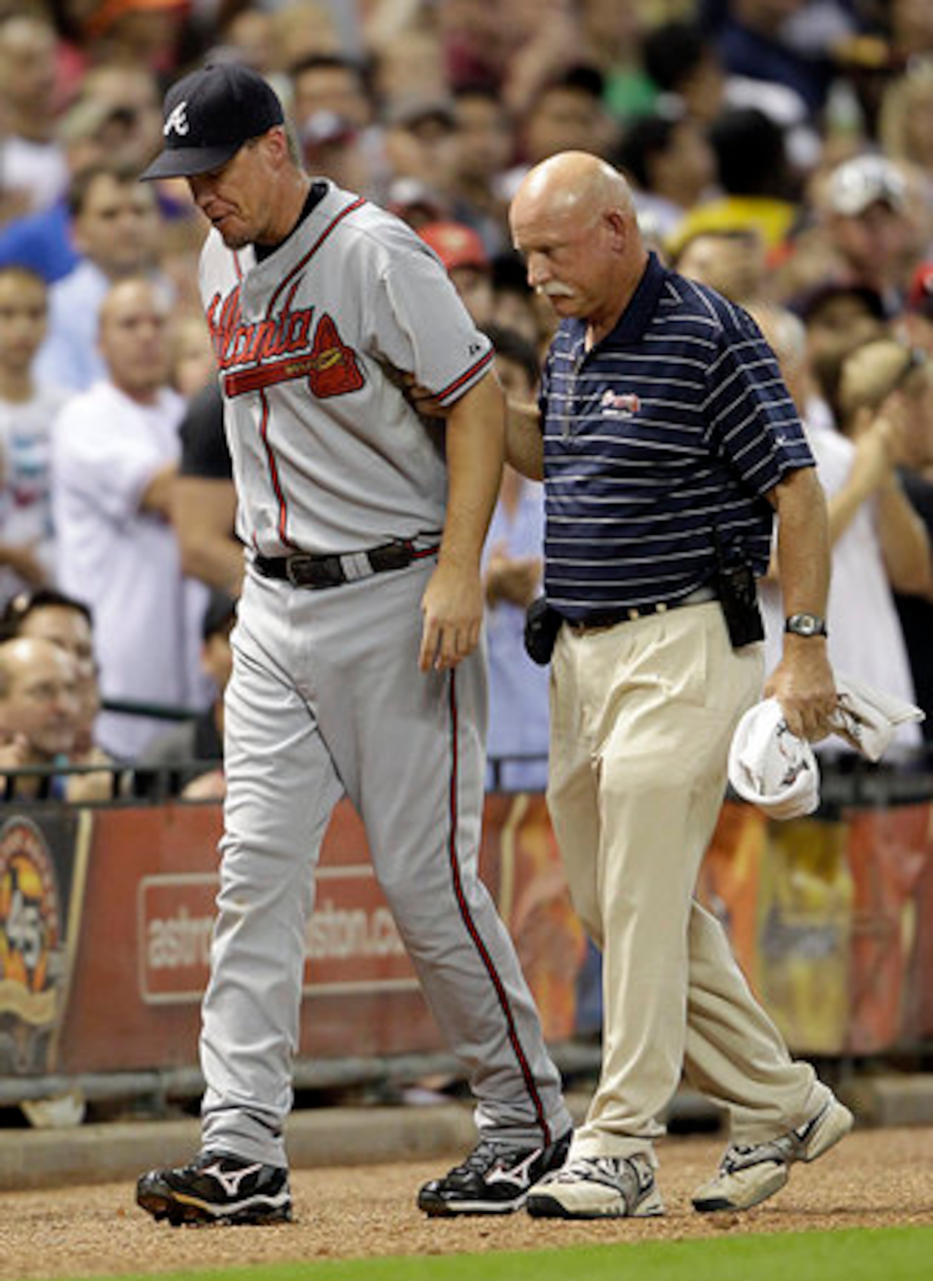 Chipper Jones walks off the field in Houston with the help of trainer Jeff Porter. Jones hurt his left knee on the play. His agent says it's an anterior cruciate ligament.