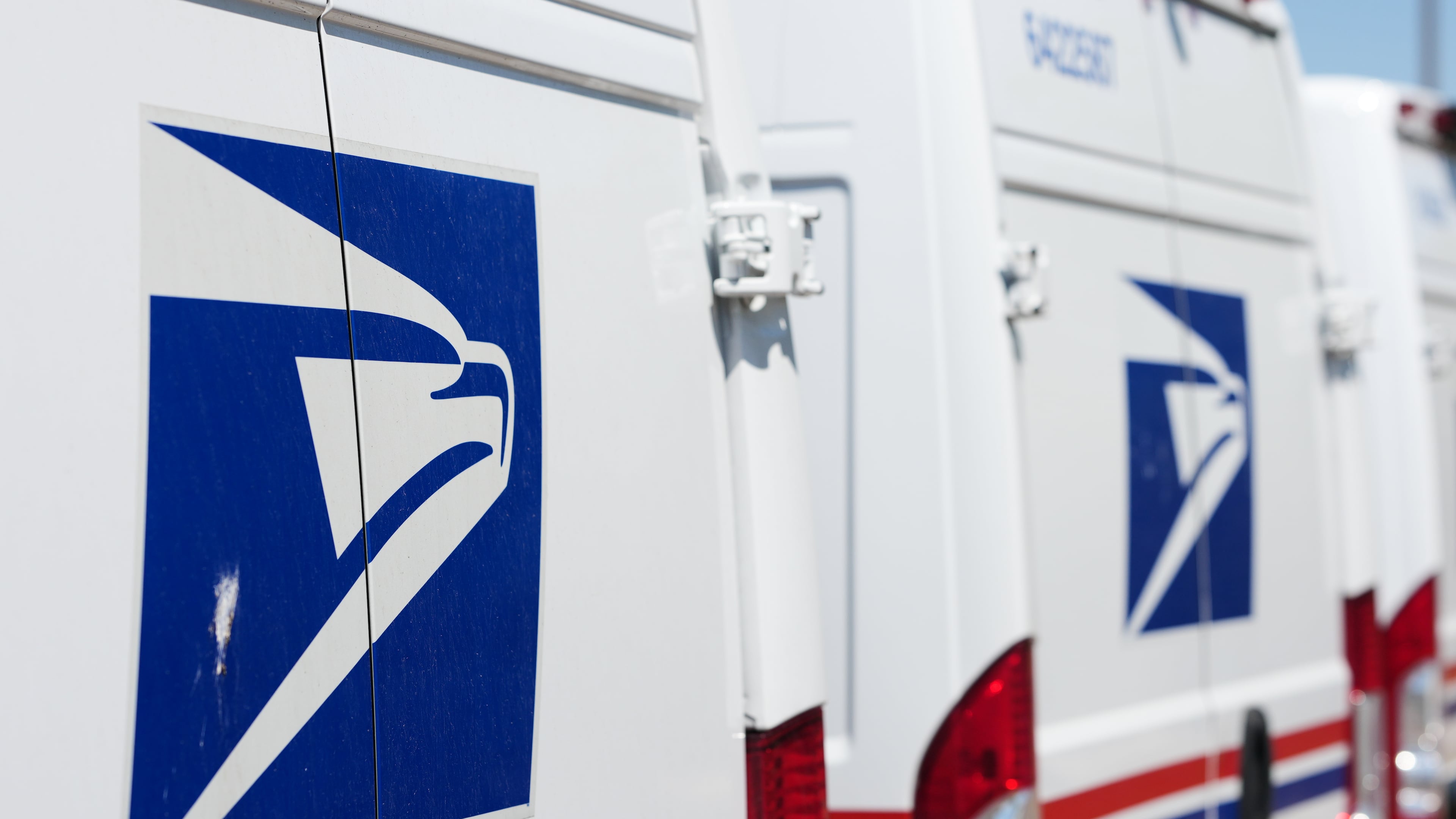 Delivery vans bearing the logo sit during a protest staged as part of a countrywide National Day of Action Tuesday, July 28, 2026, outside the main United States Postal Service headquarters in northeast Denver. (AP Photo/David Zalubowski)