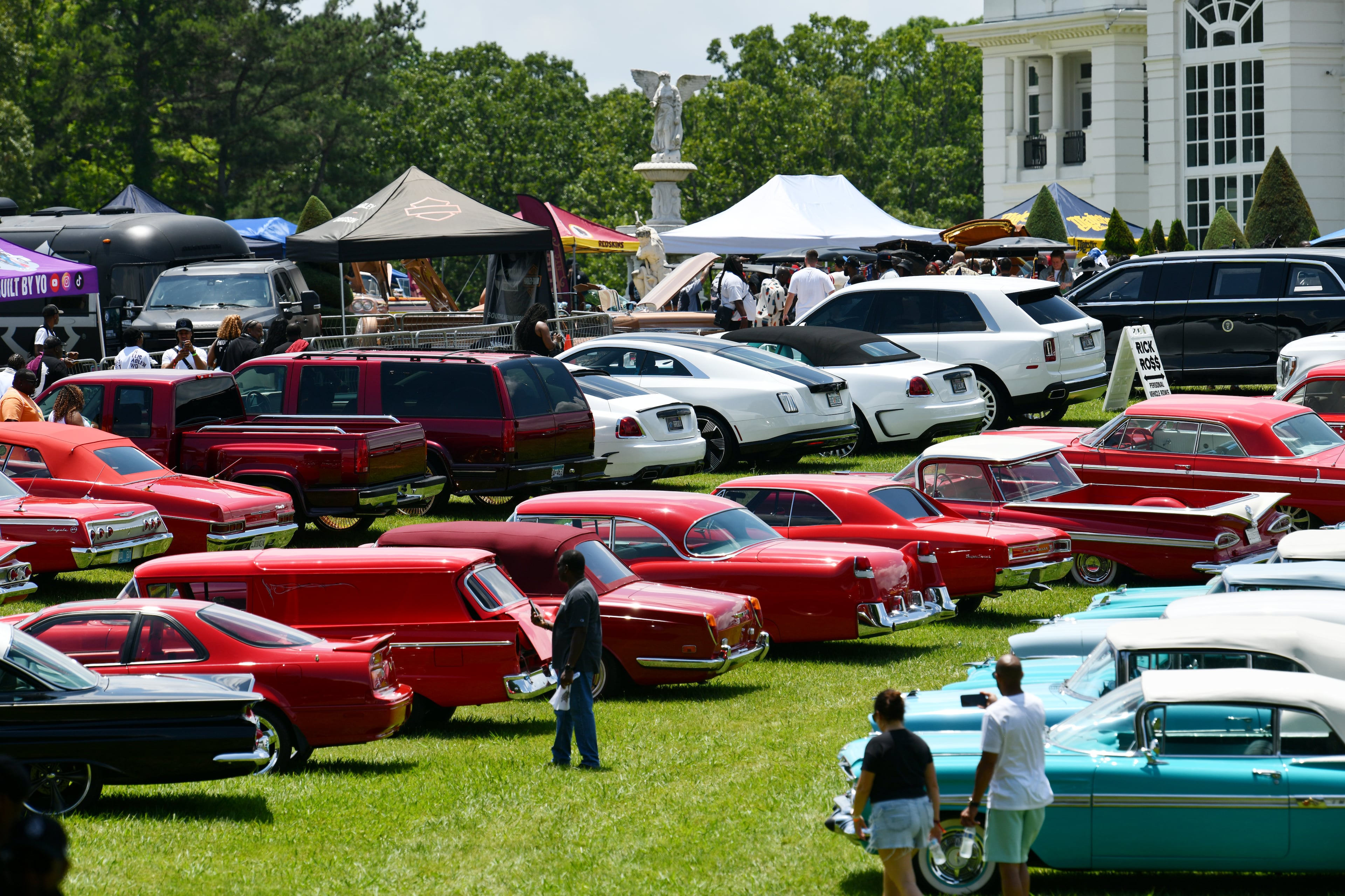 Attendees walk through fleets of classic/custom automobiles, luxury vehicles, boats, RVs and trailers on the front of the mansion during the 4th Annual Rick Ross Car and Bike Show, Saturday, June 7, 2025, in Fayetteville. The 4th Annual Rick Ross Car and Bike Show will include a vendor market with more than 30 vendors, food trucks, fleets of classic/custom automobiles, luxury vehicles, boats, RVs and trailers on the front of the mansion. Stage performances include Plies, Ross' new signee Nino Breeze and Ross himself. (Hyosub Shin / AJC)