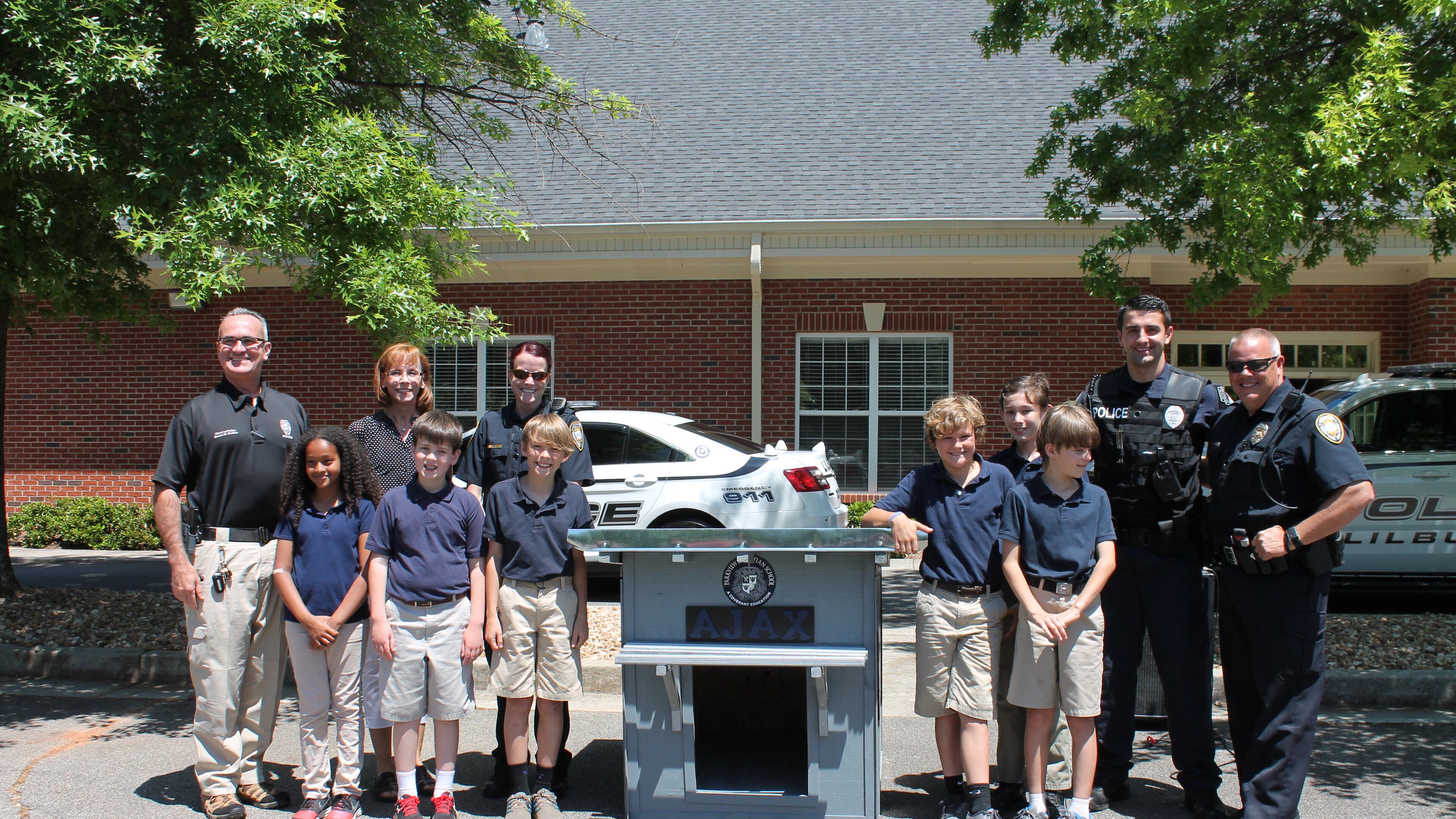 Fifth-grade students at Parkview Christian School in Lilburn pose with the doghouse they made for the Lilburn Police Department’s newest K-9, Ajax.