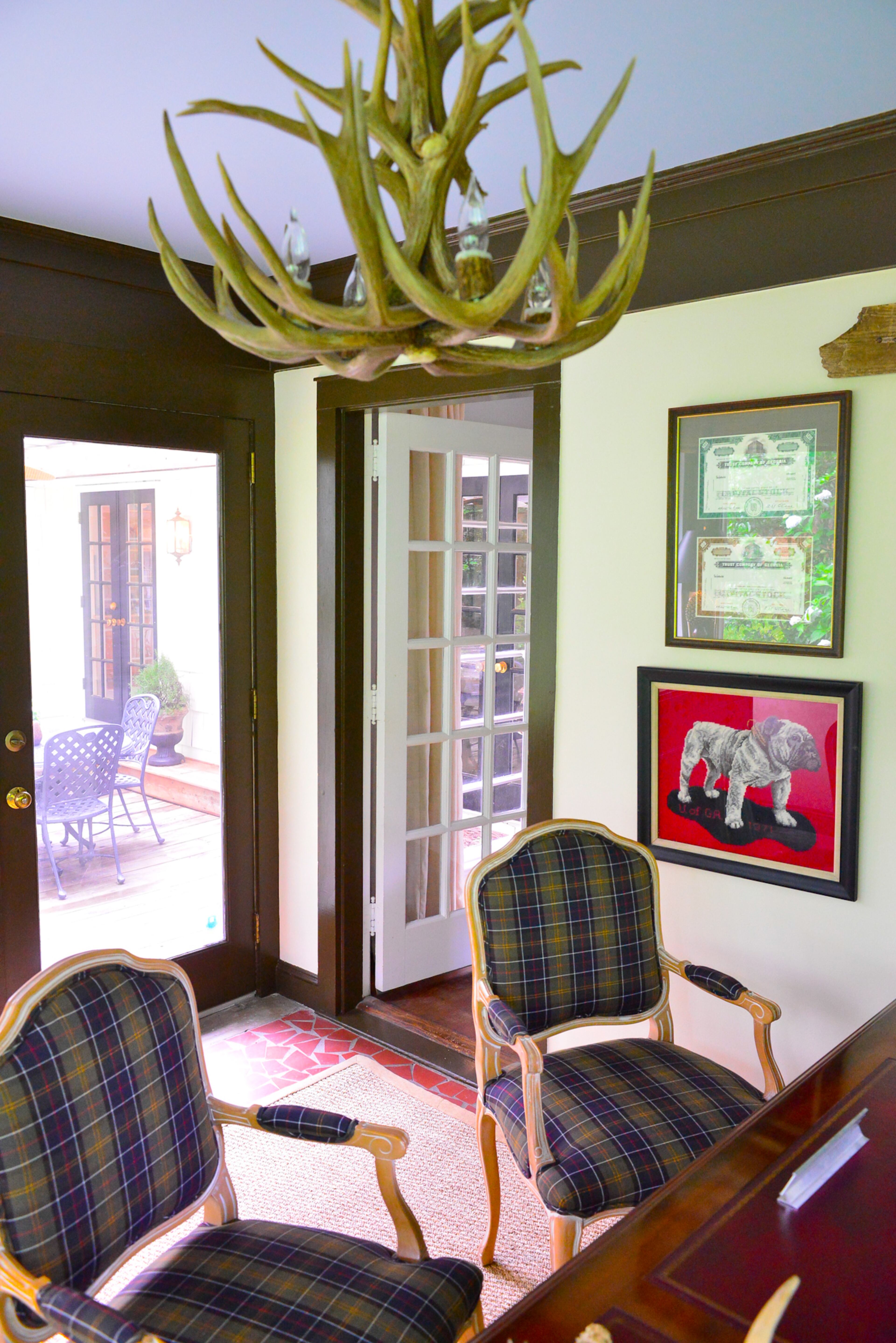 Custom chairs are covered in British tartan fabric, which was a gift from J. Barbour & Sons out of London. The fabric is used for the liner of Barbour's iconic Beaufort waxed cotton jackets. Deep crown molding enhances the traditional look of the room and offers a contrast to the light walls.