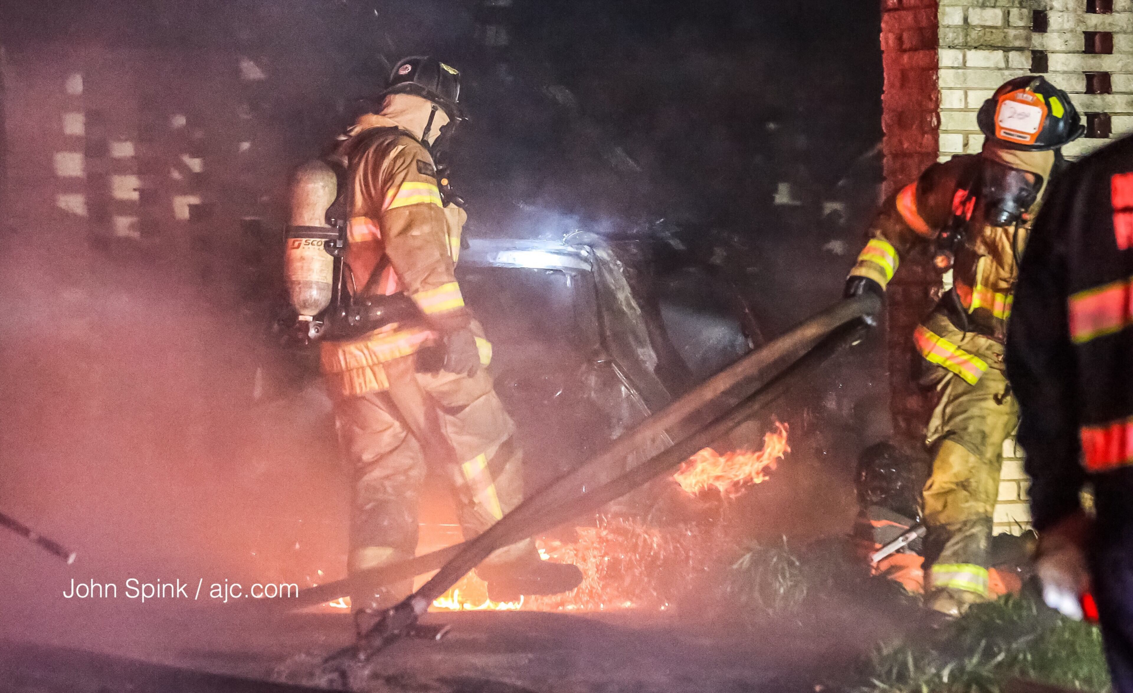 DeKalb County firefighters battled flames that engulfed two cars and a brick house early Monday on Raleigh Drive. JOHN SPINK / JSPINK@AJC.COM