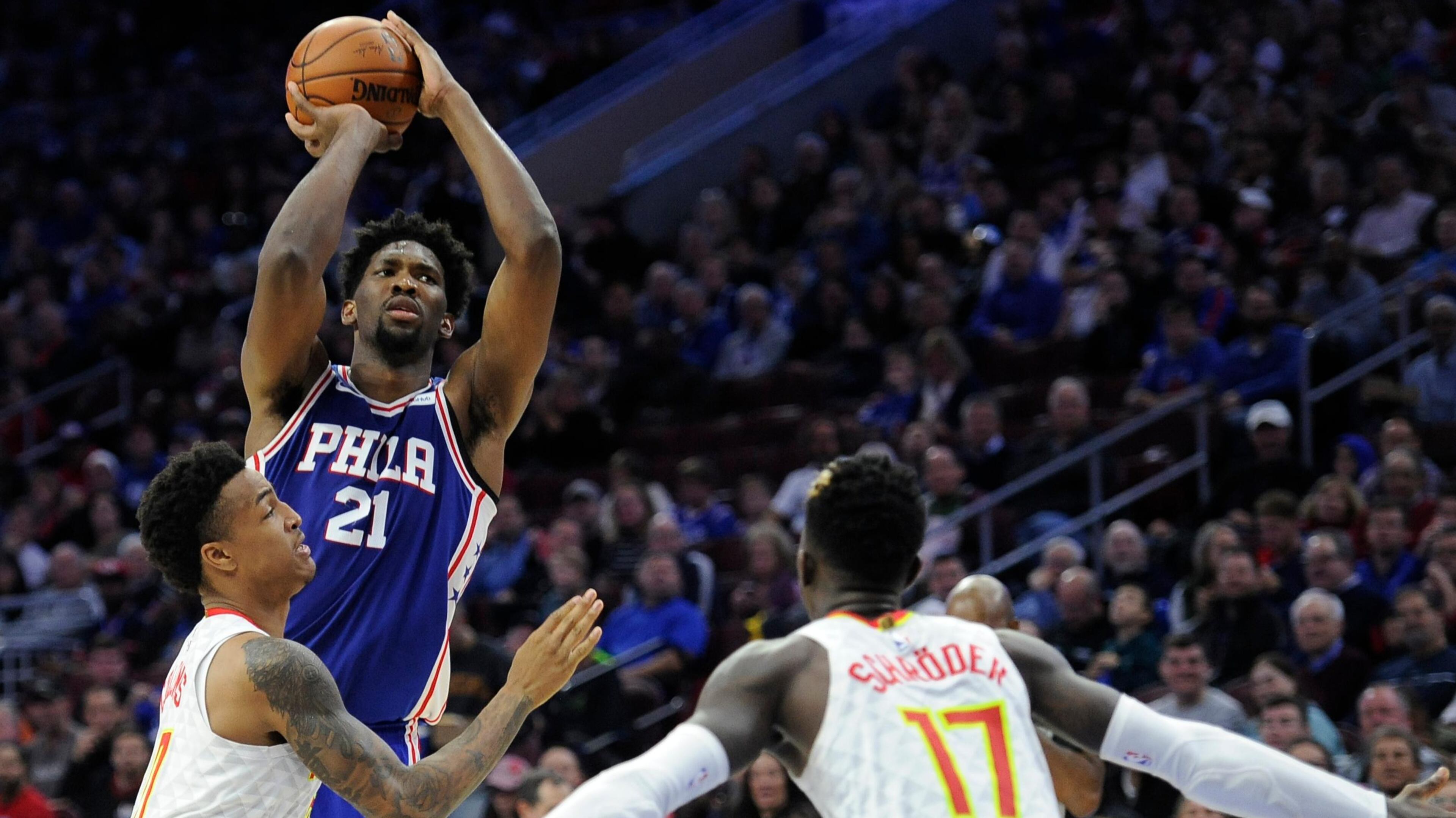 Philadelphia 76ers' Joel Embiid (21) takes a shot over Atlanta Hawks' John Collins (20) and Atlanta Hawks' Dennis Schroder (17) during the first half of an NBA basketball game, Wednesday, Nov. 1, 2017, in Philadelphia. (AP Photo/Michael Perez)