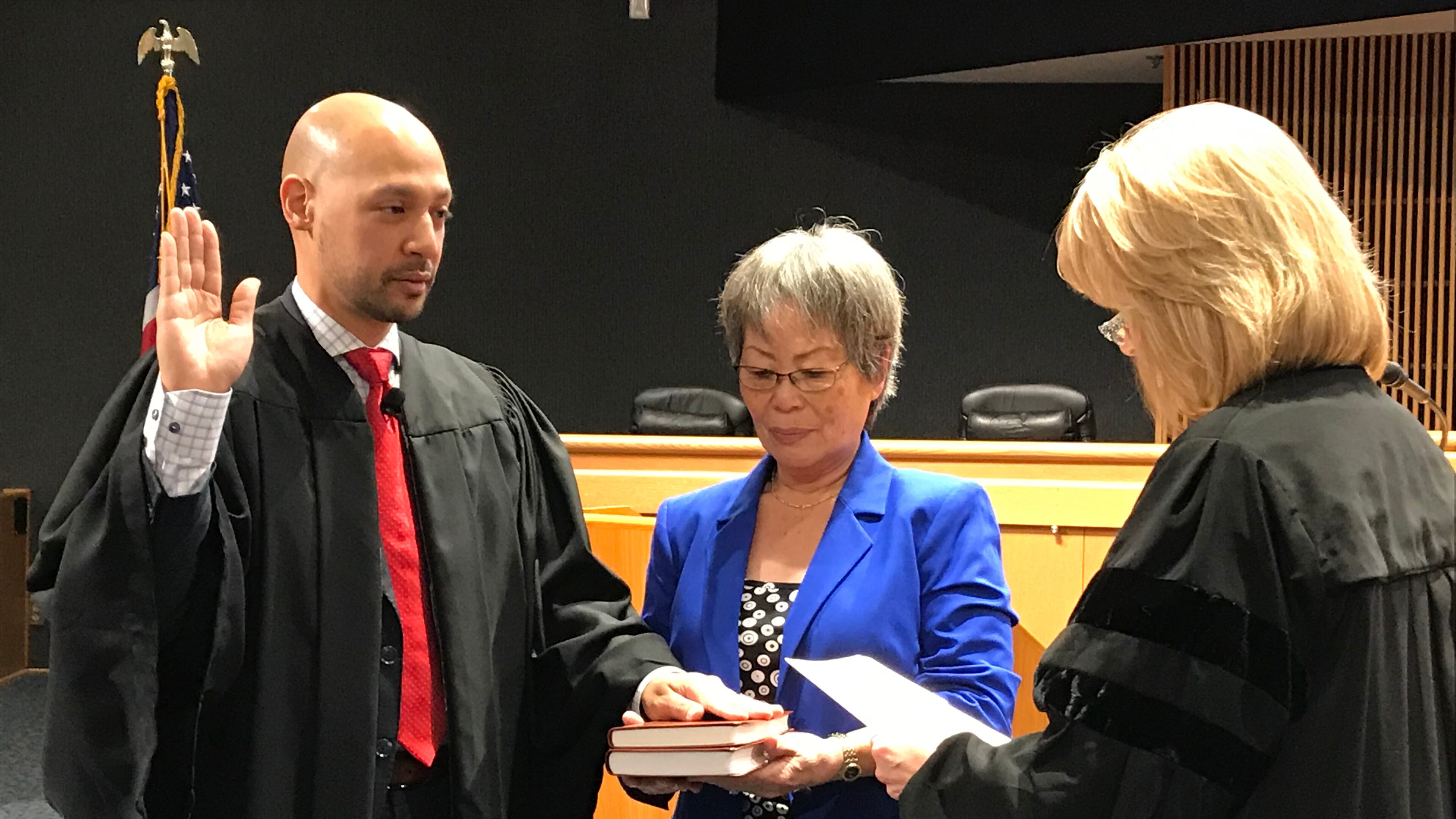 Ramon Alvarado (left) is sworn in as a Gwinnett County Recorder's Court judge on Monday by State Court Judge Emily Brantley (right) as his mother, YuSun Alvarado, looks on. Alvarado is the first Hispanic judge in Gwinnett County's history. TYLER ESTEP / TYLER.ESTEP@AJC.COM