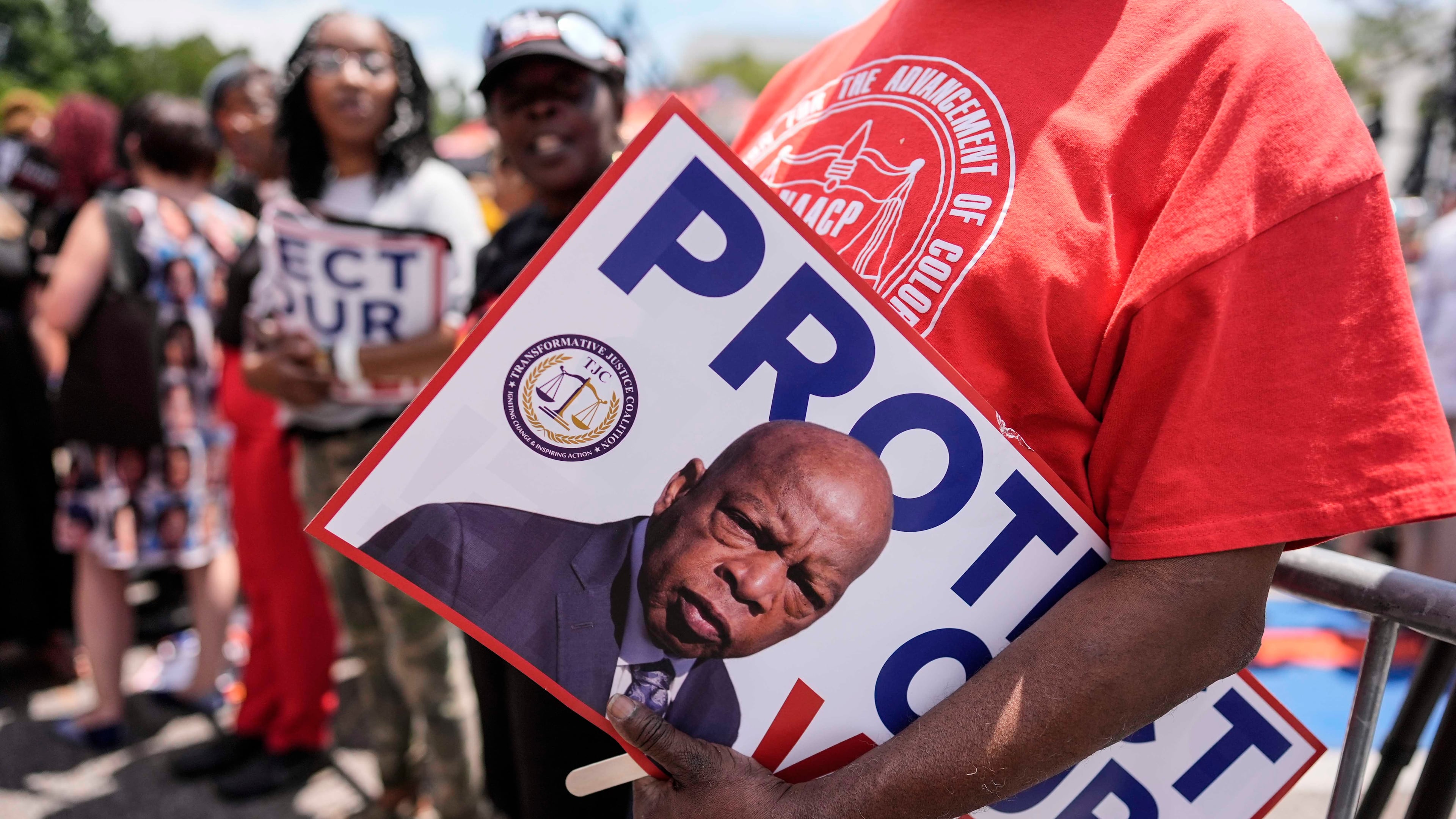A protestor holds a sign of the late Georgia Congressman John Lewis during a voting rally, Saturday, May 16, 2026, in Montgomery, Ala. (Mike Stewart/AP)
