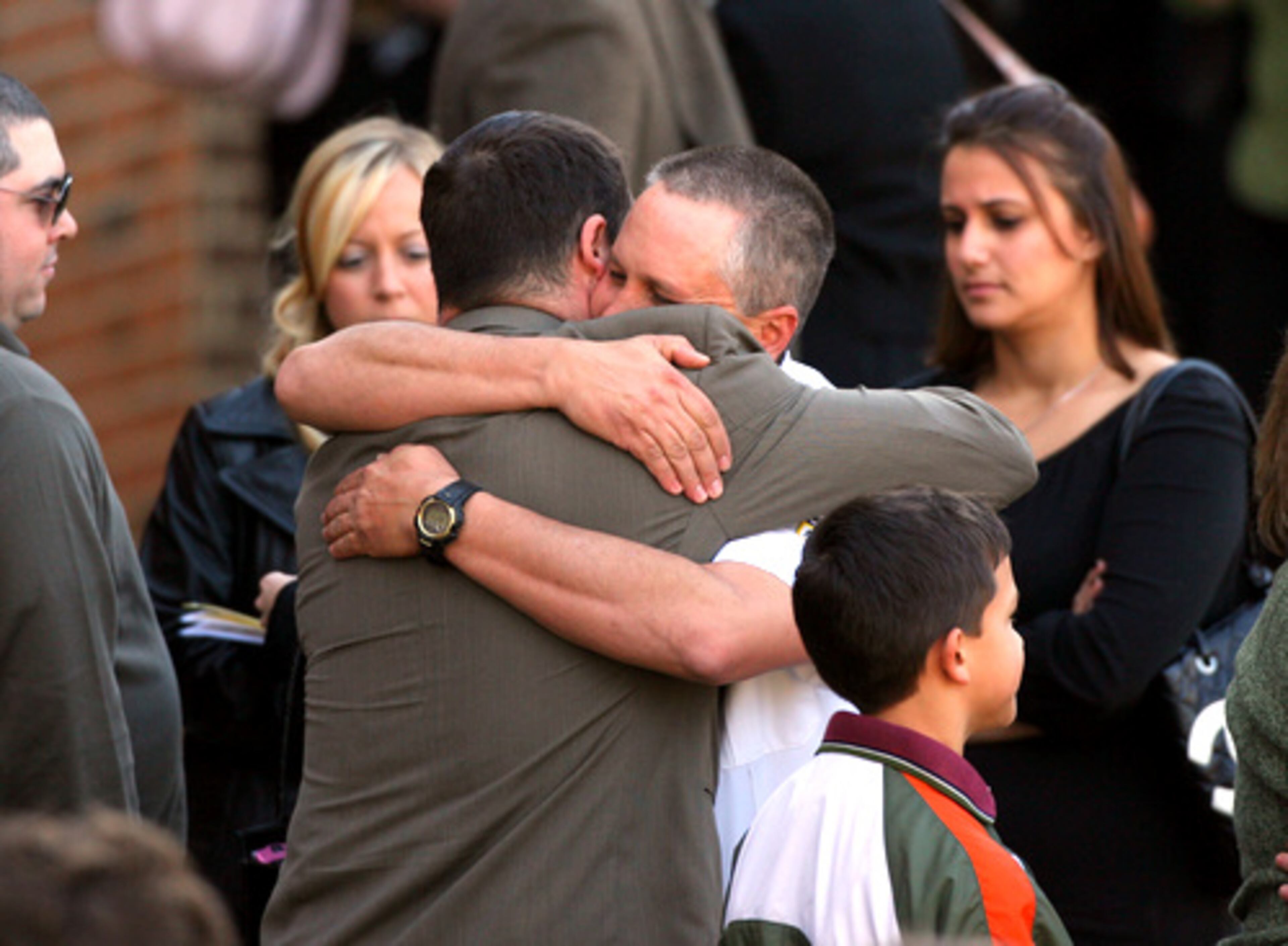 Mourners embrace following the service.