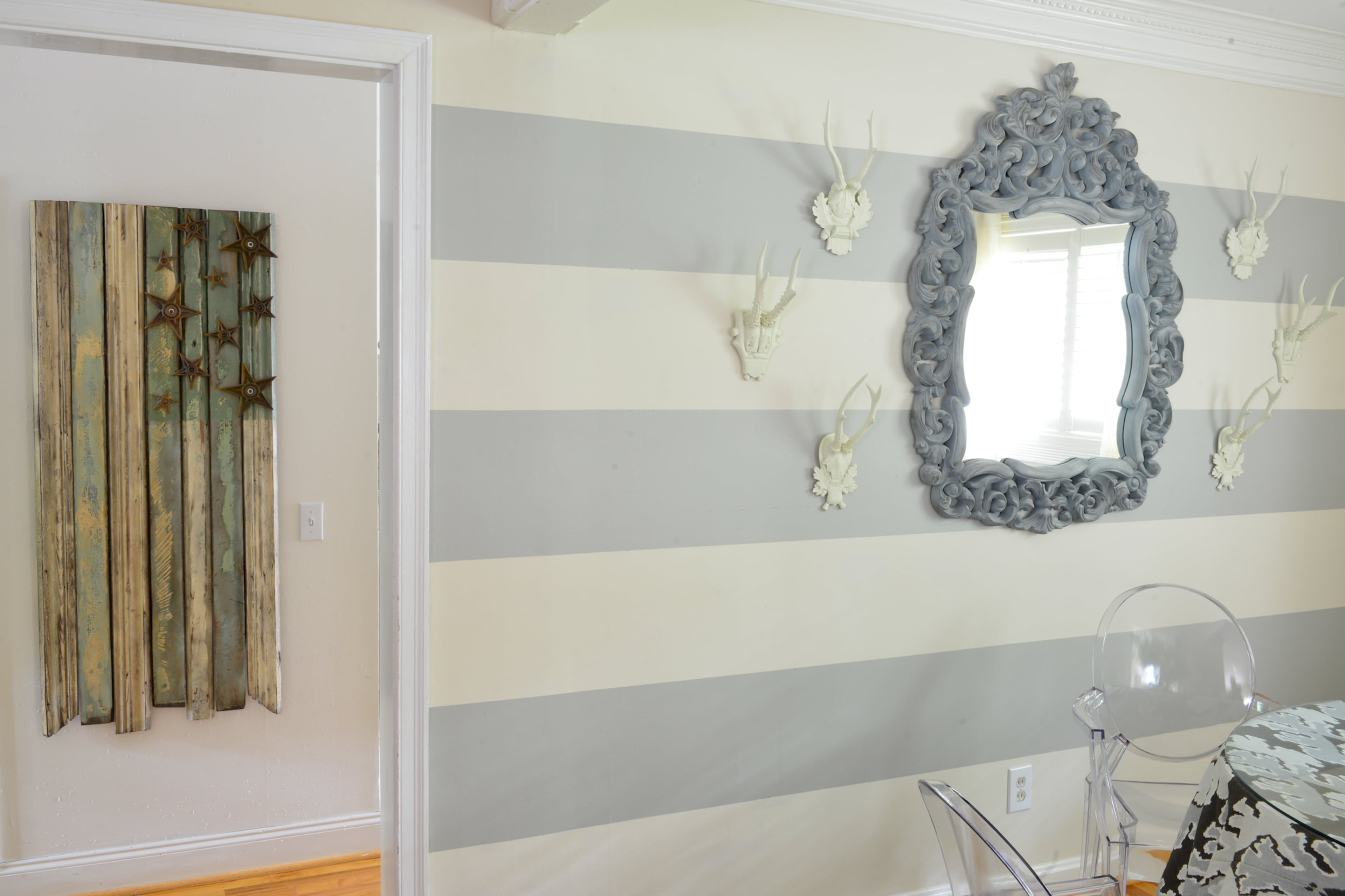 The gray-and-white striped wall in the dining room, which Betsy Clay says draws in people's eyes and gives the illusion of a larger space. On the same wall, a mirror from The Dump was transformed by Clay and her mother, who covered up the black shiny finish with gray paint and car polish.