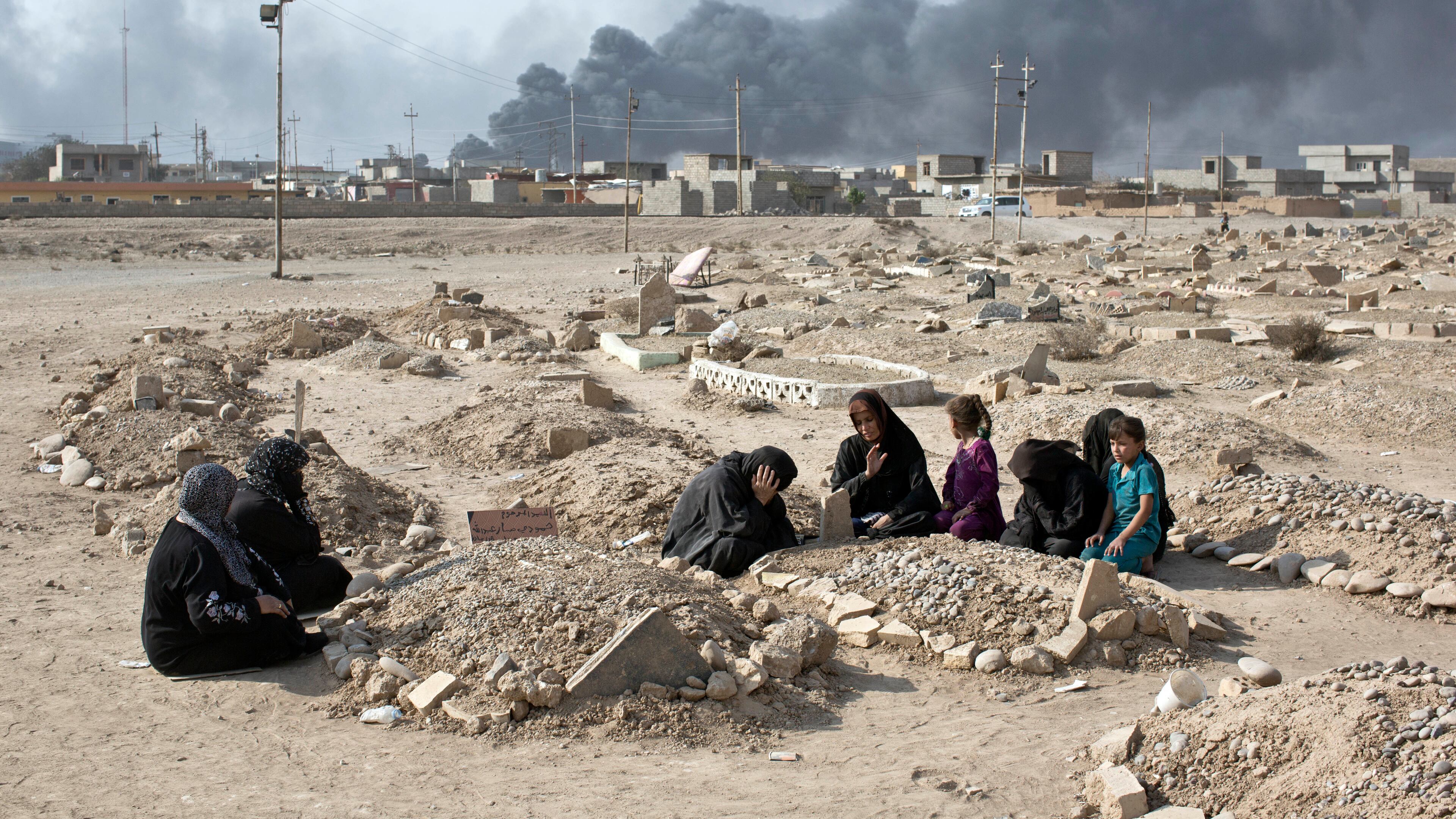 A family grieves over a grave of a family member at a graveyard damaged by Islamic State extremists in Qayara, some 31 miles, 50 km, south of Mosul, Iraq, Thursday, Oct. 27, 2016. When IS overran Qayara more than two years ago, the extremist group began destroying headstones at the local graveyard, telling residents they were forbidden because they did not exist at the time of the prophet. (AP Photo/Marko Drobnjakovic)