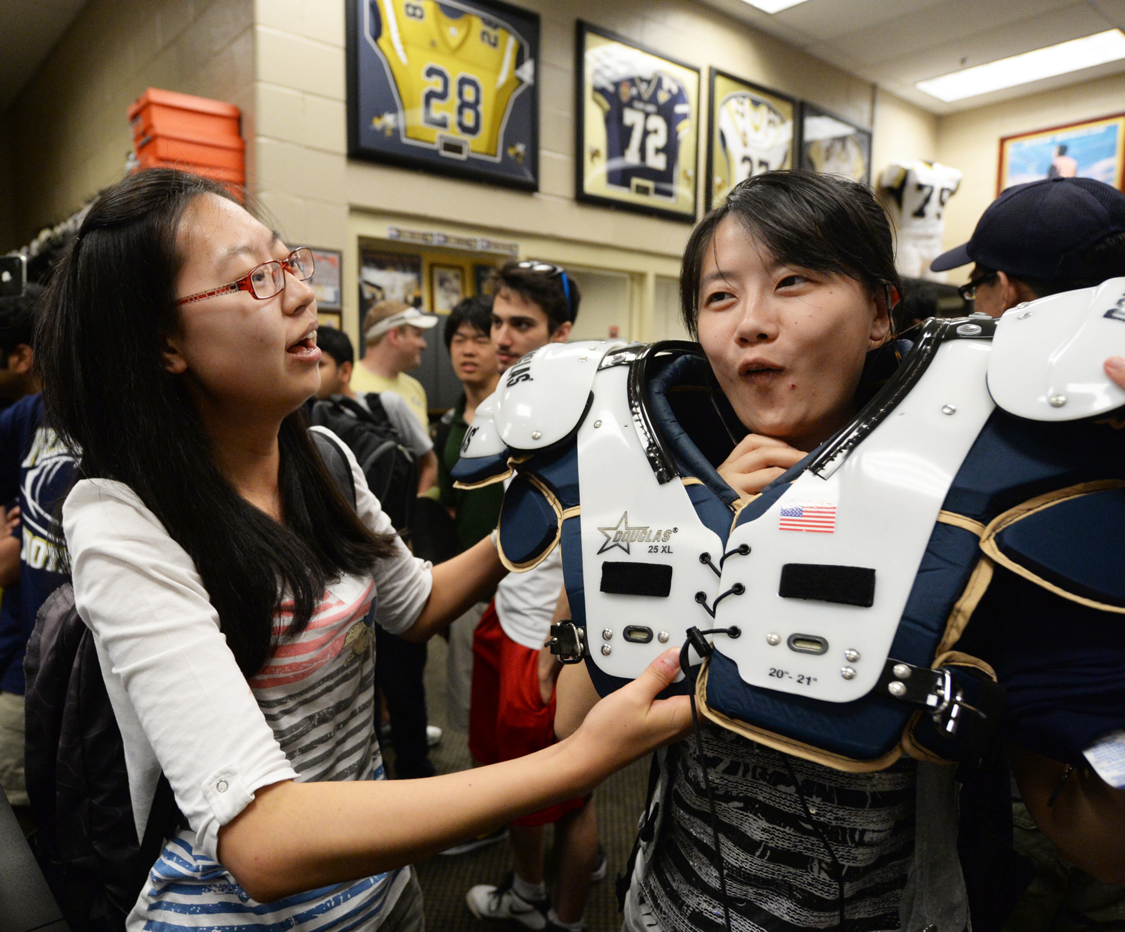 Georgia Tech student Xing Zhang, China, helps Emma Gu, China, put on some shoulder pads.