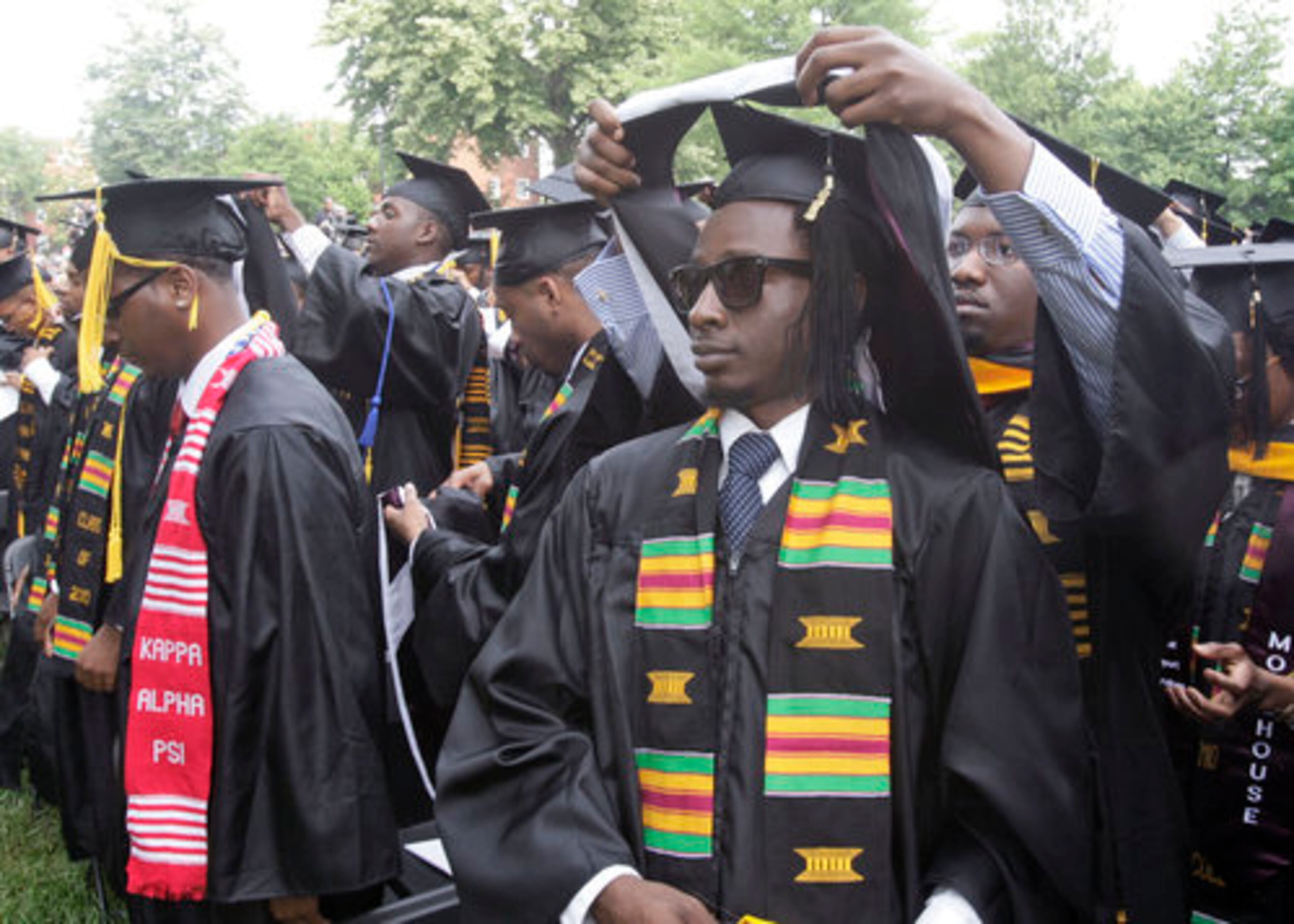 Before walking up to receive diplomas, each graduate places a graduation hood on the graduate to his right. Desmond Diggs, right, places a hood over Modibo Diabate.