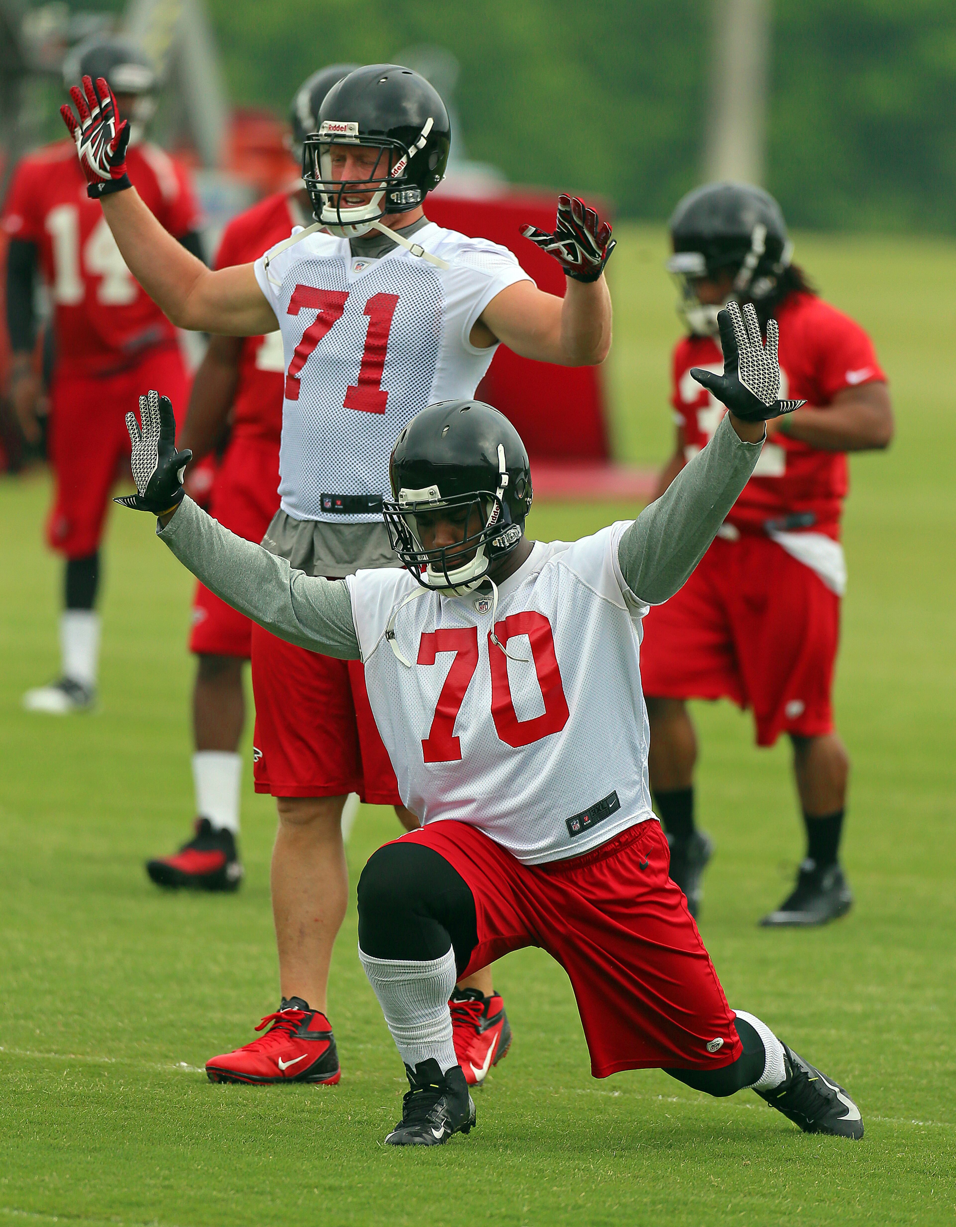 Falcons defensive ends Brandon Thurmond (front) and Kroy Biermann run a stretching drill. CURTIS COMPTON / CCOMPTON@AJC.COM