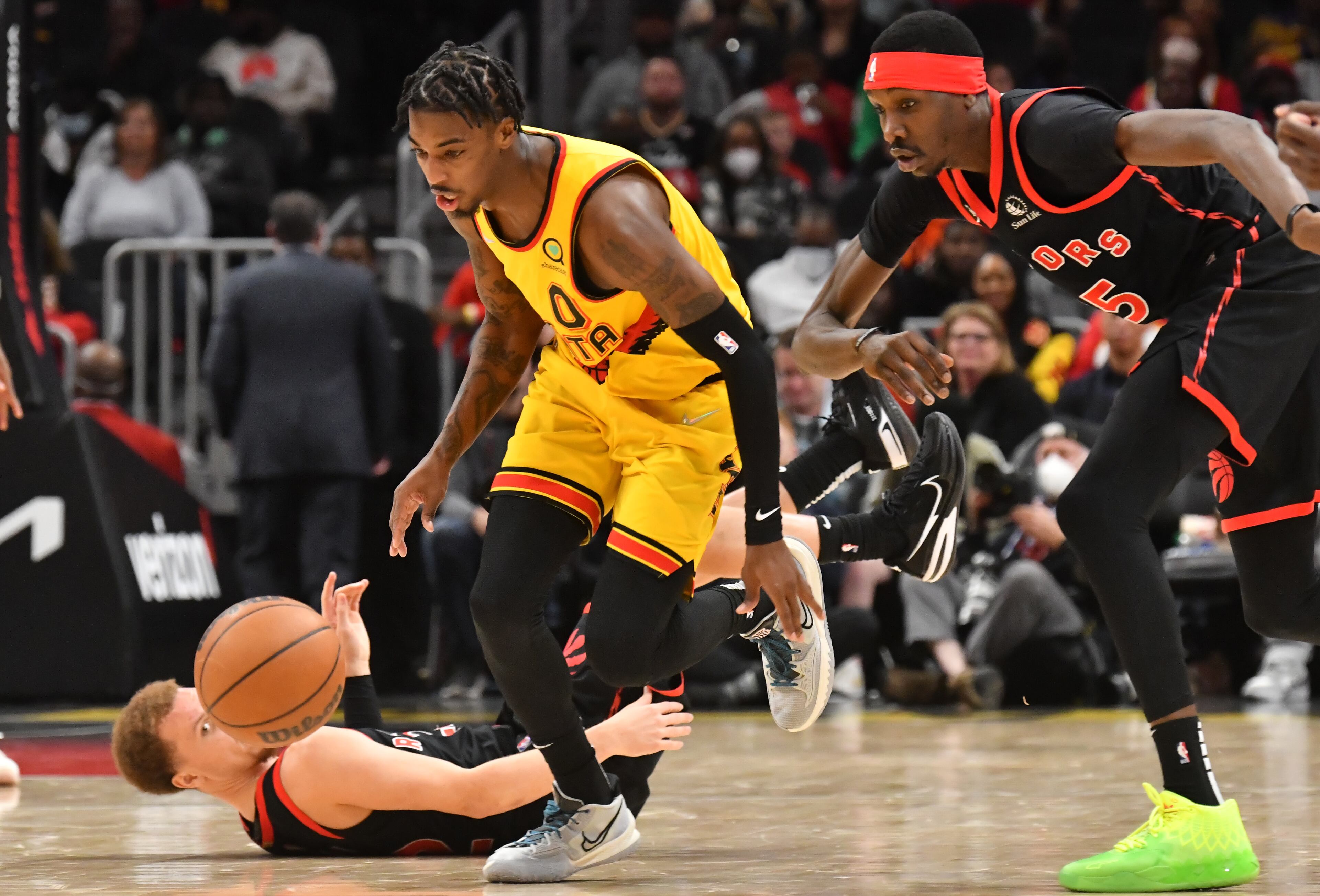 Atlanta Hawks guard Delon Wright (0) and Toronto Raptors forward Chris Boucher (right) go for a loose ball during the second half at State Farm Arena on Saturday, February 26, 2022. The Hawks won 127-100. (Hyosub Shin / Hyosub.Shin@ajc.com)