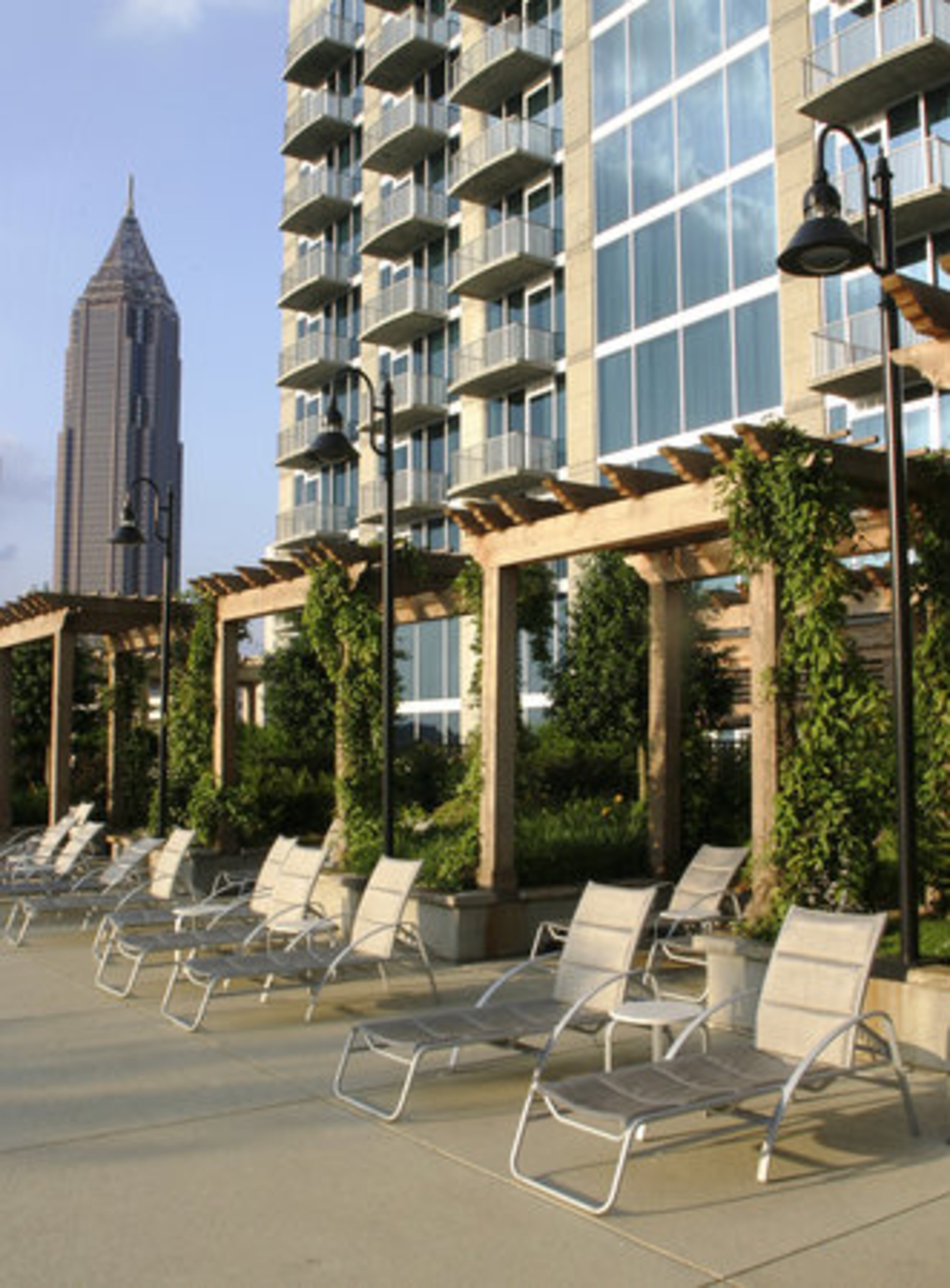 Poolside lounge chairs are set for appreciating the setting sun as it drenches the luxury high-rise Twelve at Centennial Park with a golden glow.