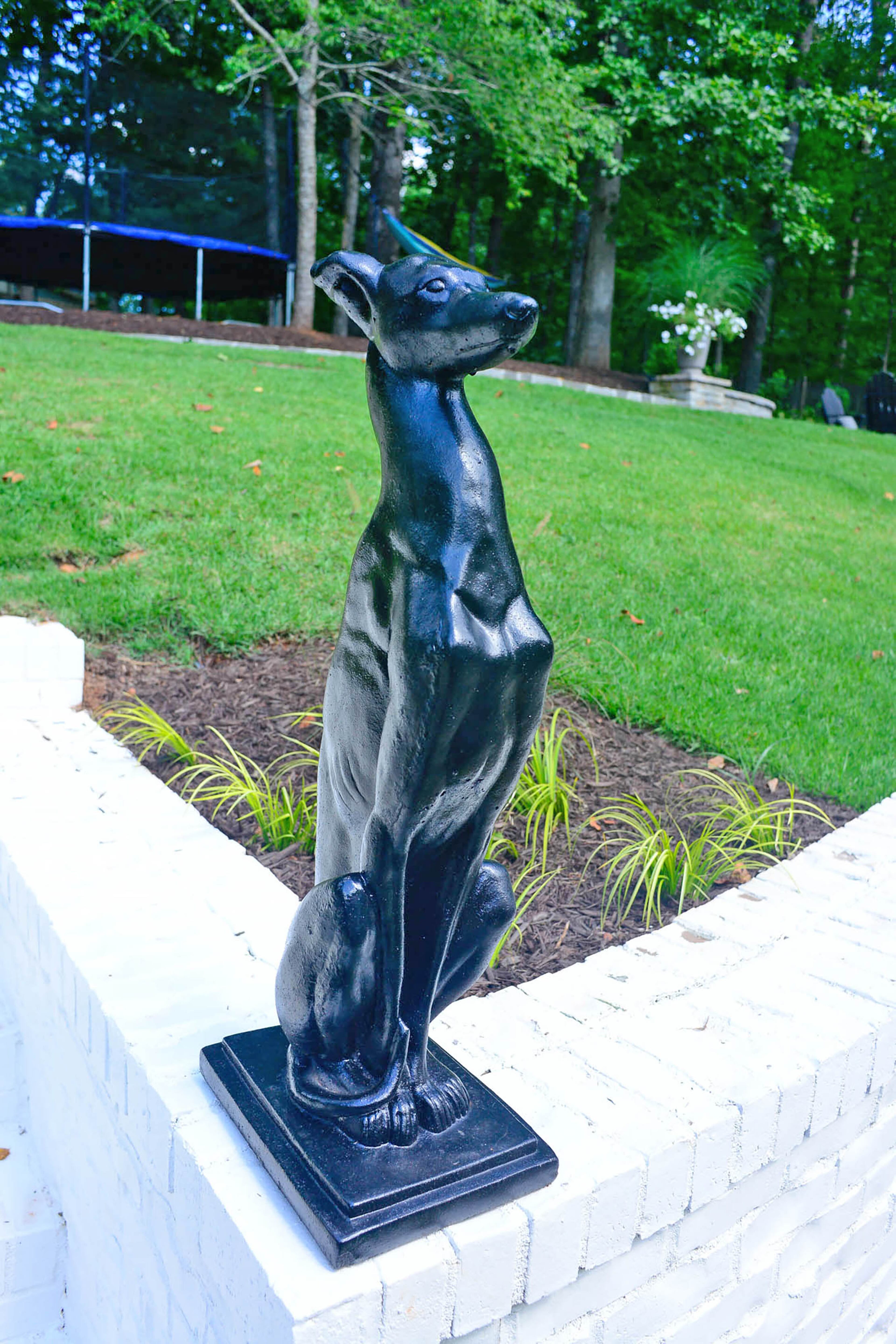 Vintage antique greyhound sculptures, from City Antiques & Interior Arts in Roswell, are perched along the backyard stairs. Edee painted them black to contrast with the white brick.
