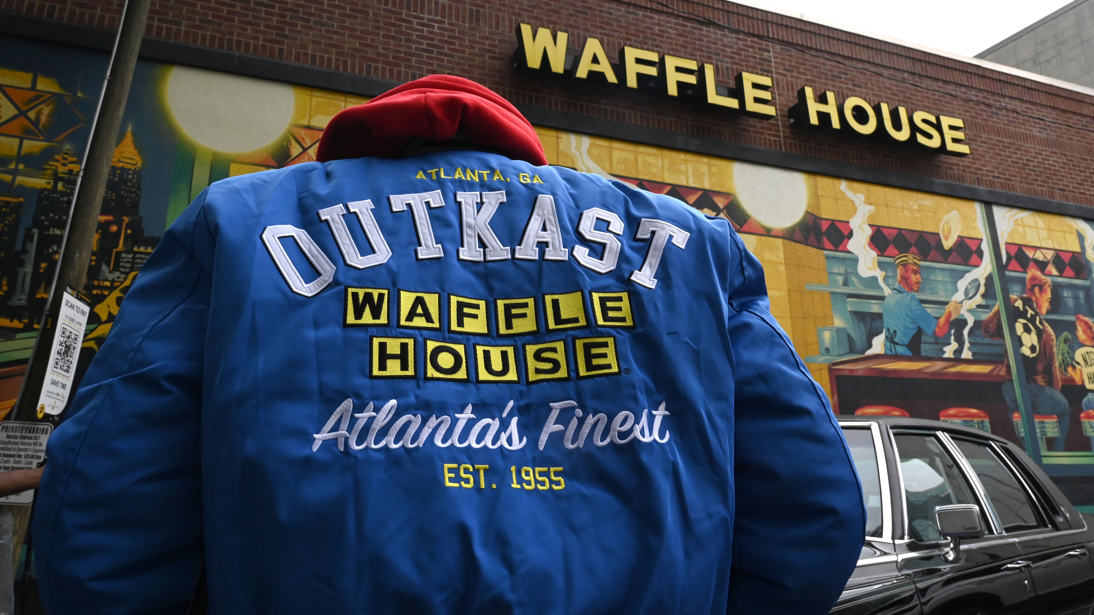 A man wearing an limited-edition jacket from the Outkast and Waffle House collaboration poses during an exclusive launch event at the Centennial Olympic Park Waffle House on Friday, Oct. 2, 2026, in Atlanta. Outkast and Waffle House launched a limited-edition apparel and accessories collection celebrating Atlanta’s music and diner culture, highlighted by a pop-up event at the Centennial Olympic Park Waffle House. (Hyosub Shin/AJC)