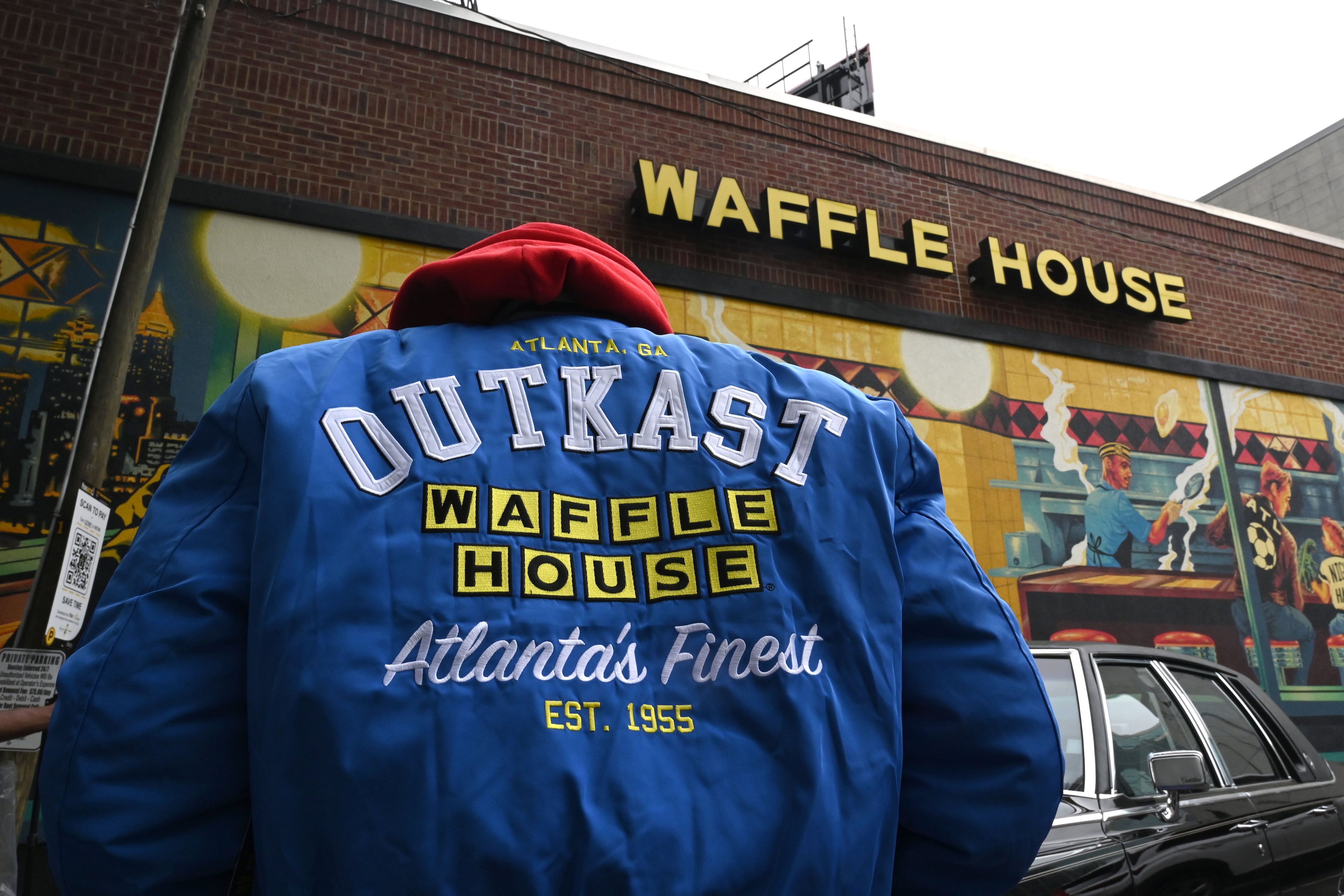 A man wearing an limited-edition jacket from the Outkast and Waffle House collaboration poses during an exclusive launch event at the Centennial Olympic Park Waffle House on Friday, Oct. 2, 2026, in Atlanta. Outkast and Waffle House launched a limited-edition apparel and accessories collection celebrating Atlanta’s music and diner culture, highlighted by a pop-up event at the Centennial Olympic Park Waffle House. (Hyosub Shin/AJC)