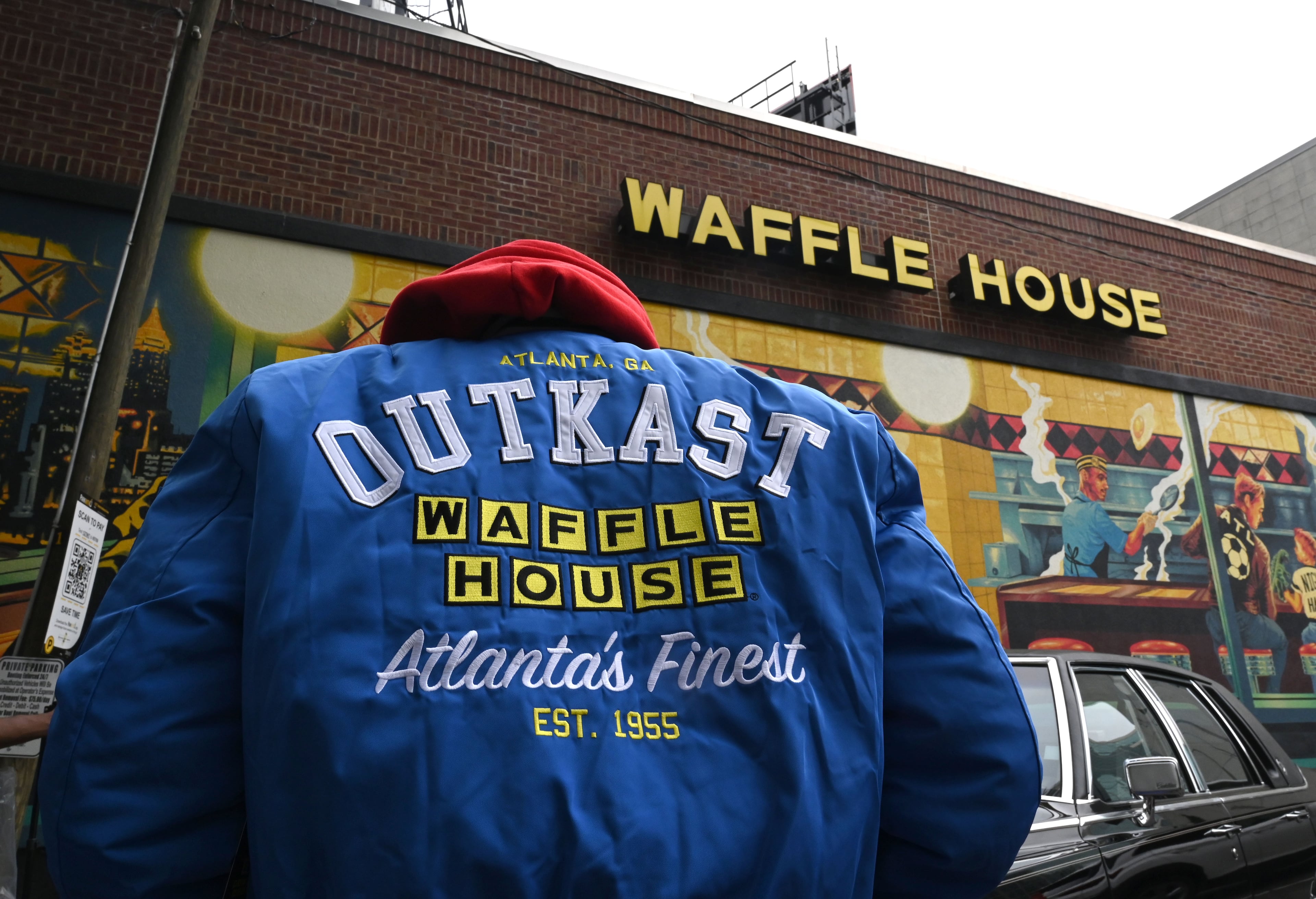 A man wears an limited-edition jacket from the Outkast and Waffle House collaboration during an exclusive launch event at Centennial Olympic Park Waffle House on Friday, Oct. 2, 2026, in Atlanta. Outkast and Waffle House launched a limited-edition apparel and accessories collection celebrating Atlanta’s music and diner culture, highlighted by a pop-up event. (Hyosub Shin/AJC)