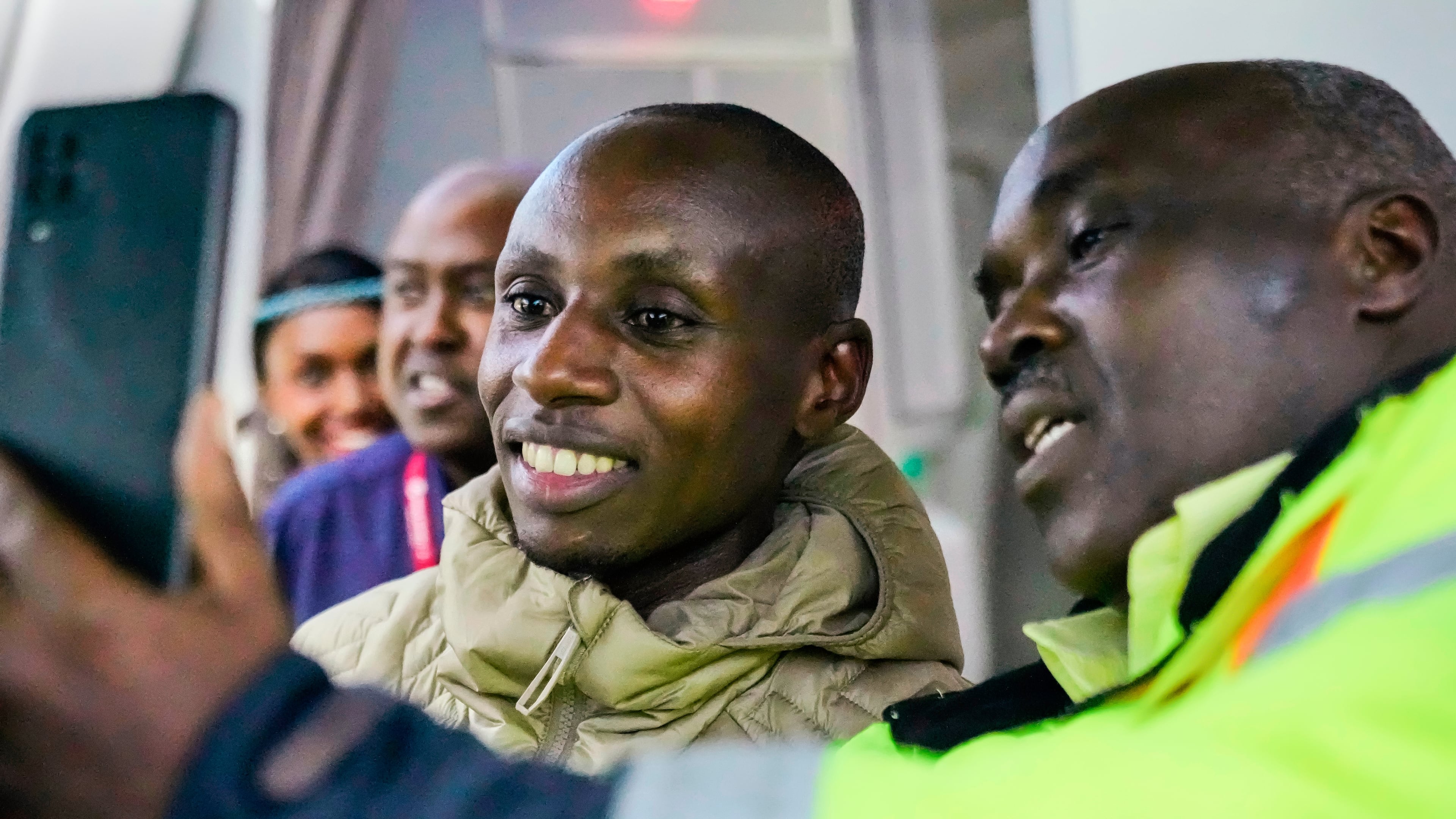 Sabastian Sawe poses for a selfie with an airport worker after arriving on a plane from London, Wednesday, April 29, 2026, at Jomo Kenyatta International Airport in Nairobi, Kenya, after setting a new world record in the marathon. (AP Photo/Brian Inganga) CORRECTION: Corrects spelling of first name to Sabastian, not Sebastian