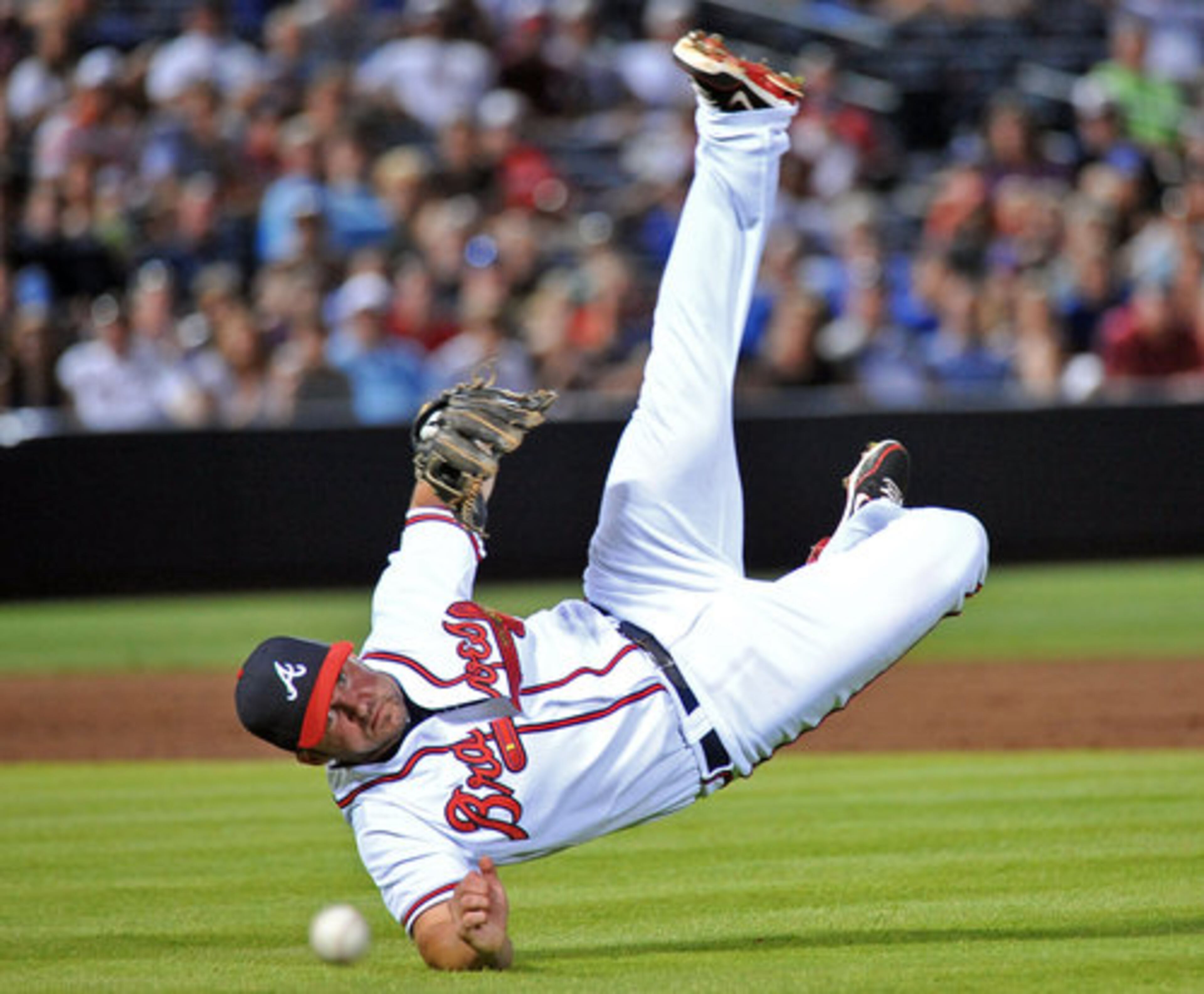 Atlanta Braves Dan Uggla (26) falls to the ground as he throws to first base after catching a ground ball hit by Chicago Cubs Jeff Baker (3) in the 8th inning of the final game of four-game series at Turner Field in Atlanta on Thursday, July 5, 2012.