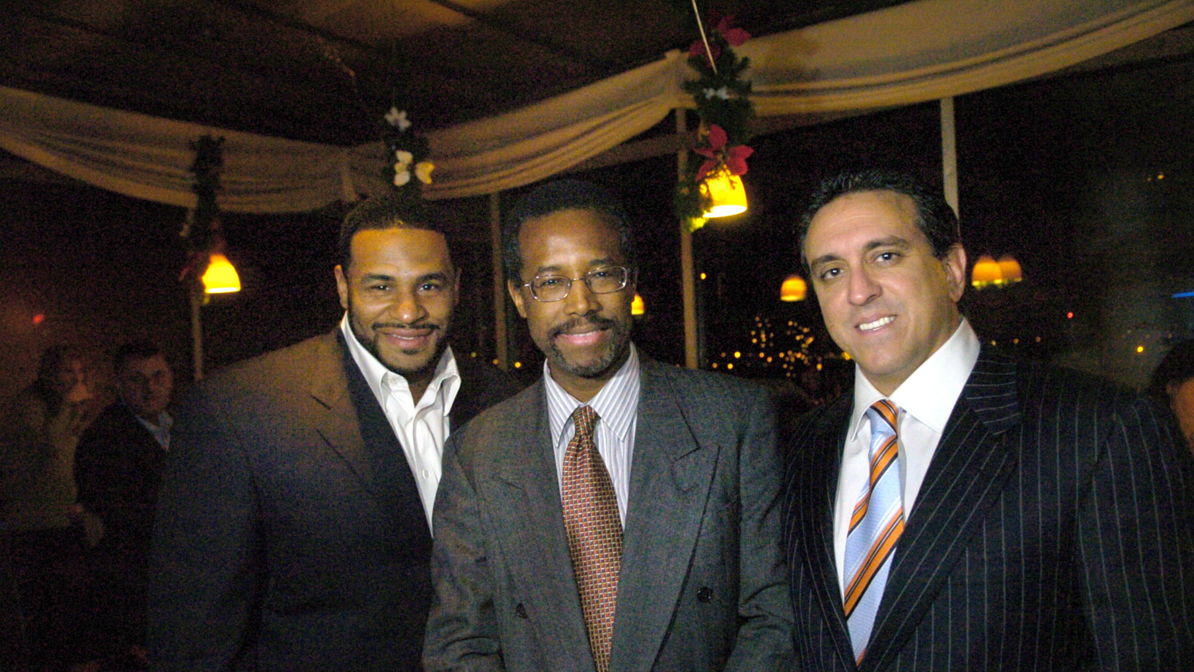 In this photo taken Dec. 1, 2005, Dr. Ben Carson, center, flanked by Dr. Al Costa, right, and then Pittsburgh Steelers running back, Jerome Bettis pose at the The Pittsburgh Carson Scholars Fund 2nd Annual Charity Auction Cocktail Event in Pittsburgh. Republican presidential contender Carson has maintained a business relationship with Costa, a close friend convicted of defrauding insurance companies and testified on his behalf, even as the candidate has called for such crimes to be punished harshly. (Andy Starnes/Pittsburgh Post-Gazette via AP)