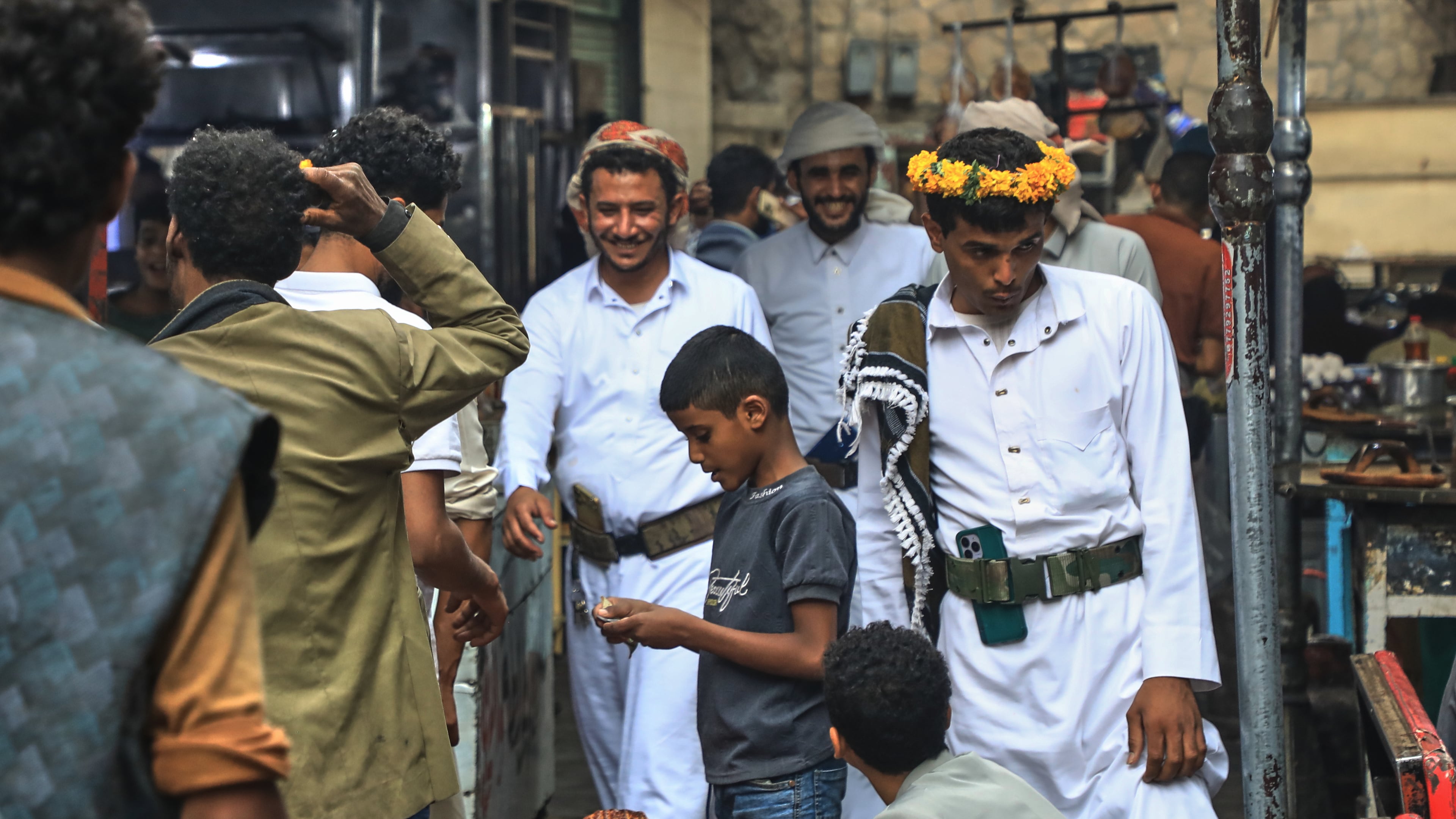 People walk past a boy selling bread at a street market in Sanaa, Yemen, Saturday, Aug. 8, 2026. (AP Photo/Osamah Abdulrahman)