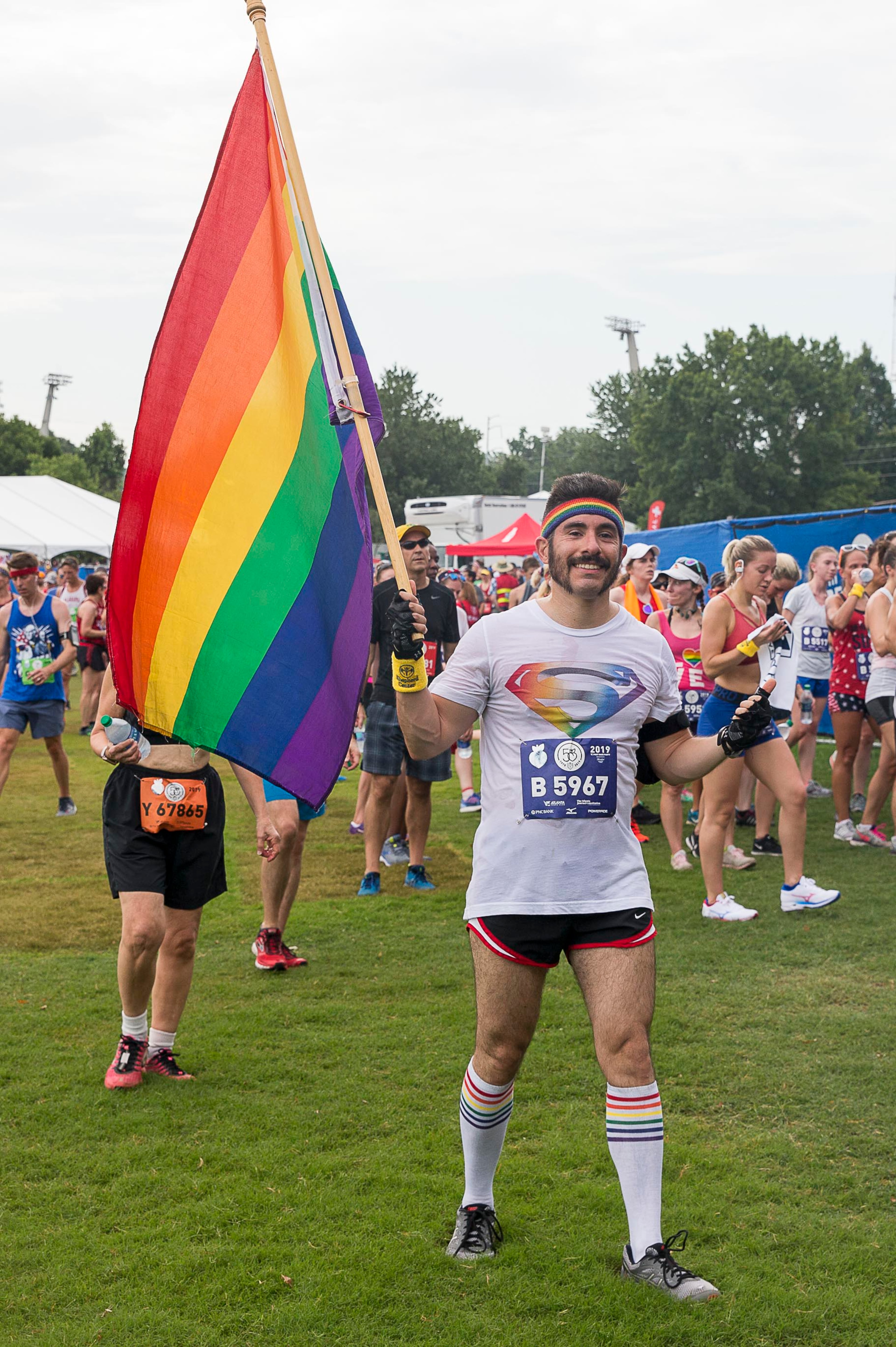 Memo Sandoval carries a rainbow flag in Piedmont Park following his completion of the AJC Peachtree Road Race in Atlanta, Thursday, July 4, 2019. (Alyssa Pointer/alyssa.pointer@ajc.com)