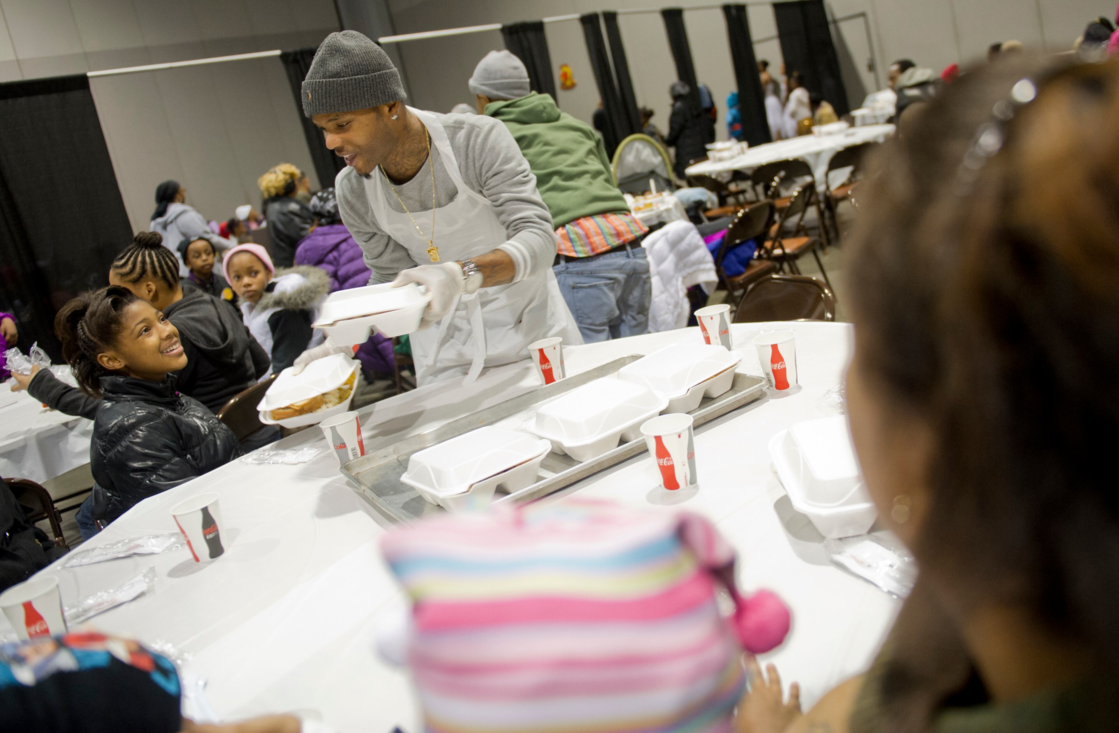 Willie Grant (center), one of hundreds of volunteers, hands a tray of food to Lakayla Shade during the Hosea Feed the Hungry and Homeless annual Thanksgiving meal at the Georgia World Congress Center in Atlanta on Nov. 28, 2013.