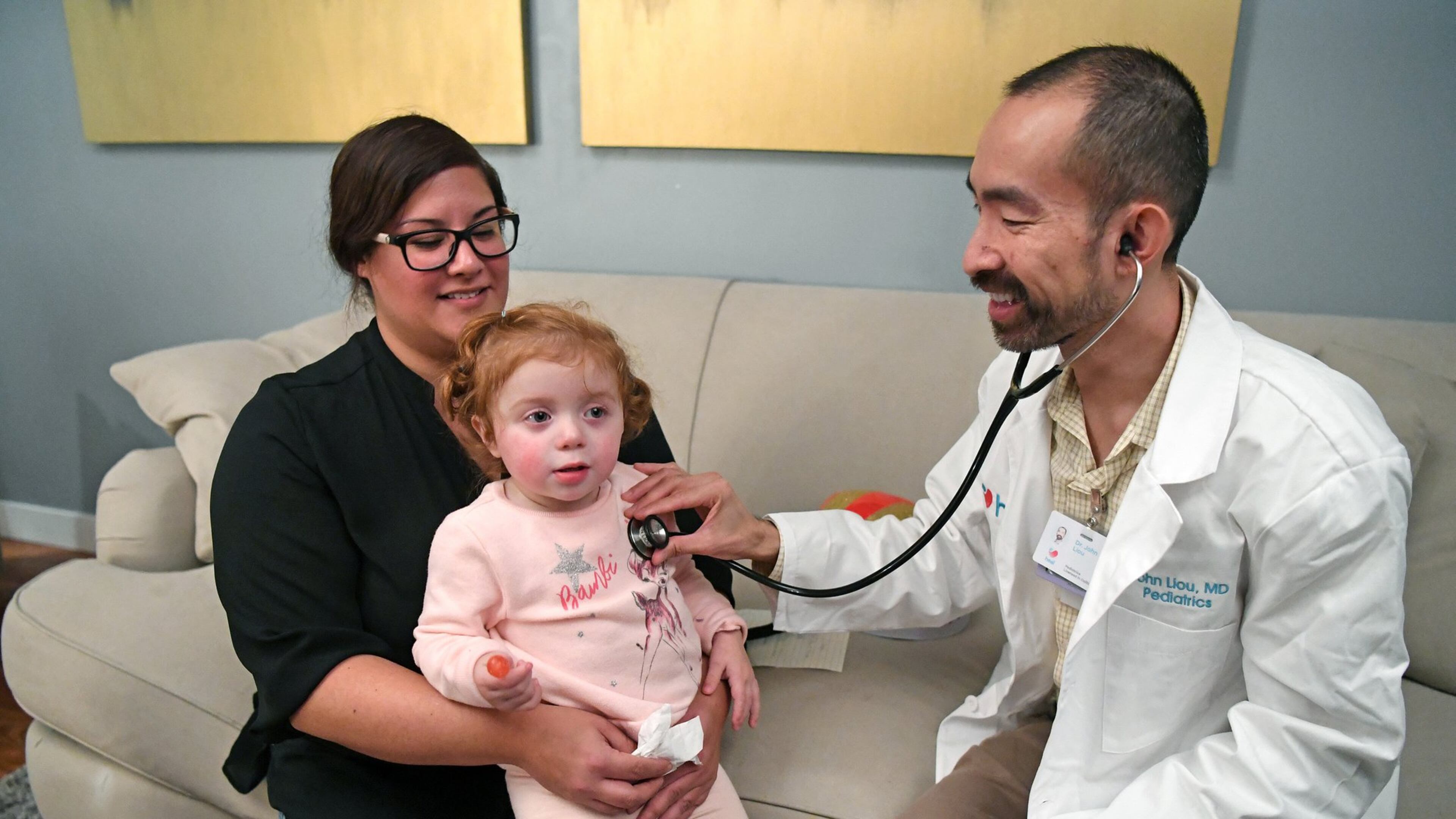 Lisa Maciel, of Hayward, holds her daughter Elyse, 2, as Heal.com pediatrician John Liou examines her on Friday, Jan. 19, 2018 at Maciel’s home in Hayward, Calif. Maciel hired Heal.com to find out if her daughter had a cold or the flu. Many people with the flu are heading to the ER and waiting for hours to see a doctor and running the risk of sitting next to others with even worse cases of the flu. Heal.com gives people another option by sending a primary care doctor to diagnose you at your home or office. (Doug Duran/Bay Area News Group/TNS)