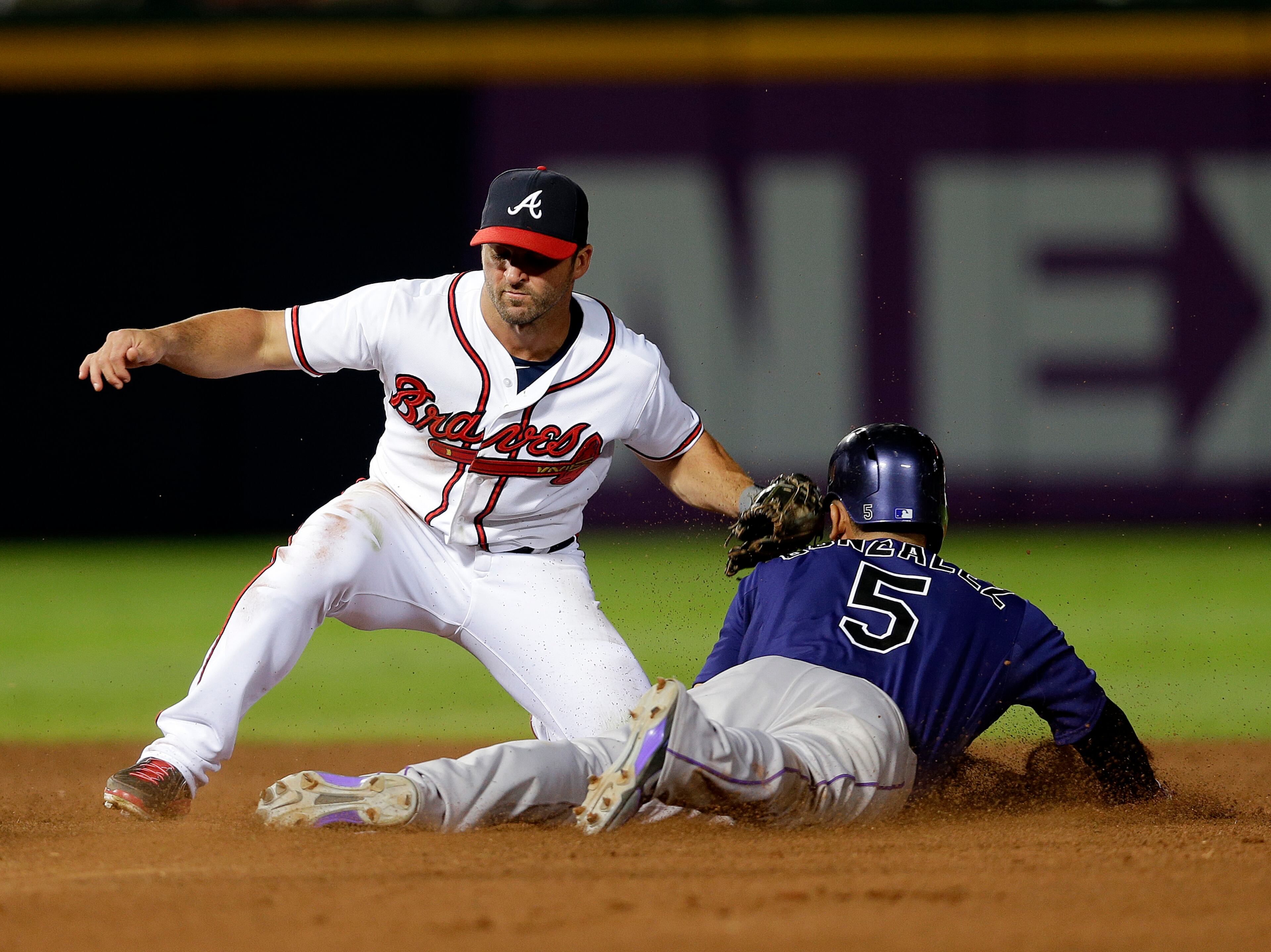 Colorado Rockies' Carlos Gonzalez, right, is tagged out by Atlanta Braves second baseman Dan Uggla, left, as he attempts to steal second base in the seventh inning.