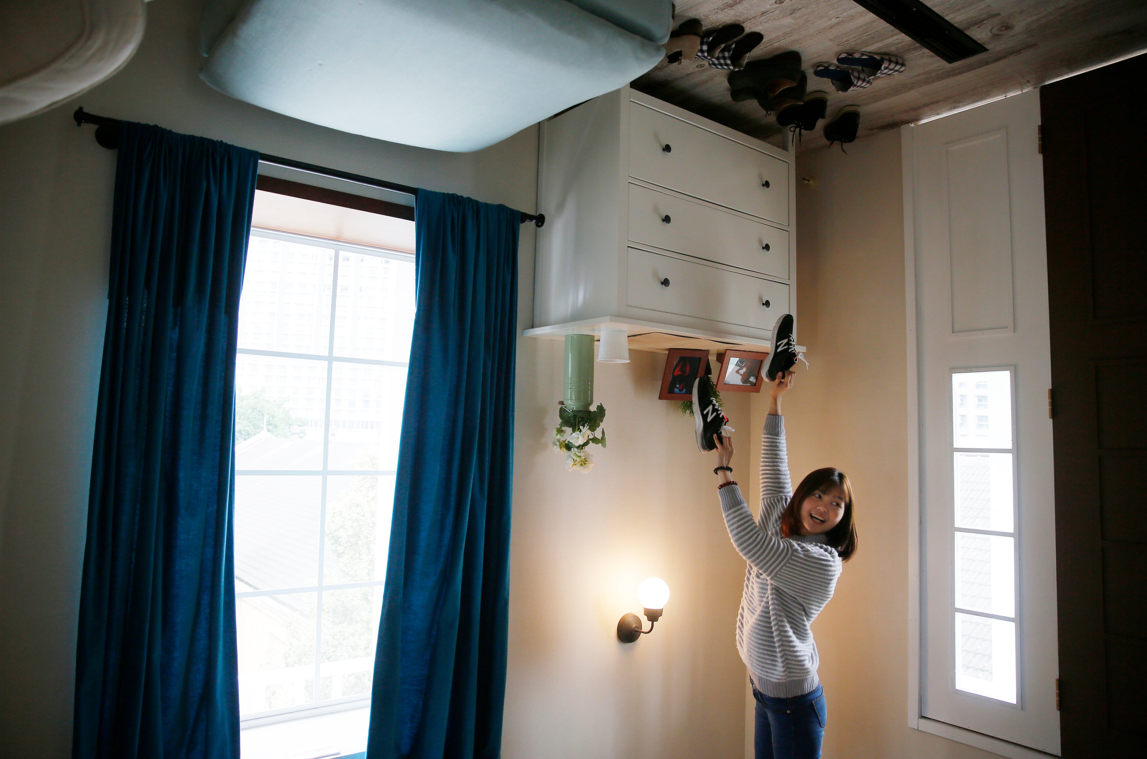 A visitor poses inside an upside-down house created by a group of Taiwanese architects at the Huashan Creative Park in Taipei, Taiwan, Tuesday, Feb. 23, 2016. With a build price of $600,000 and over 300 square meters (3,230 square feet) of floor space filled with real home furnishings, the upside-down house will continue to be on display to visitors until July 22. (AP Photo/Wally Santana)