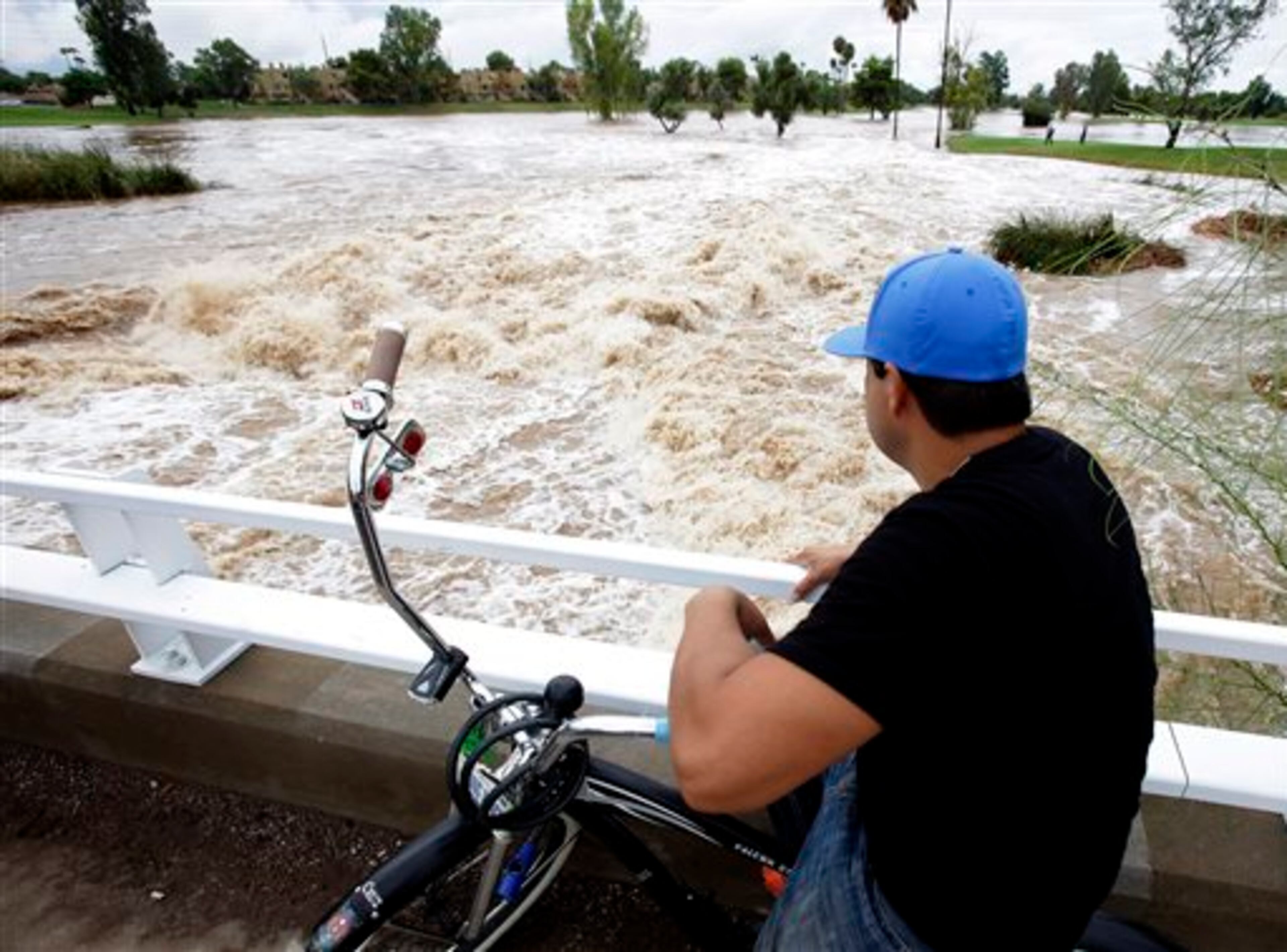 A man watches floodwaters surge under an overpass Monday, Sept. 8, 2014, in Scottsdale, Ariz. The remnants of Hurricane Norbert pushed into the desert Southwest and swamped Arizona Monday, breaking the previous record for rainfall in a single day in Phoenix. (AP Photo/Rick Scuteri)