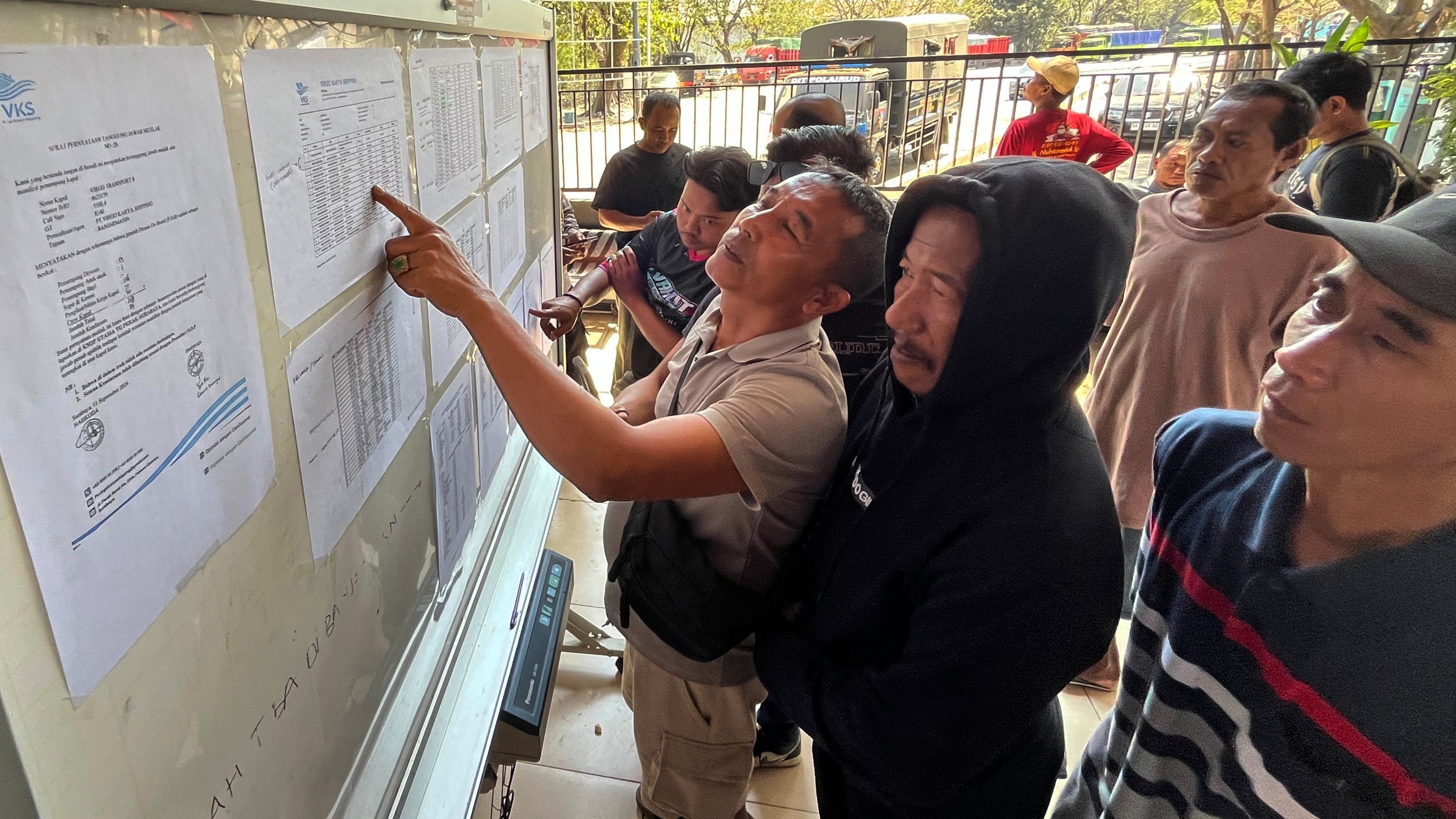 People check the passenger manifest of Virgo Transport 8 passenger ferry which overturned in bad weather in the Java Sea, at the rescuers' command center in Banjarmasin, South Kalimantan, Indonesia, Monday, Sept. 14, 2026. (AP Photo/Iman Satria)