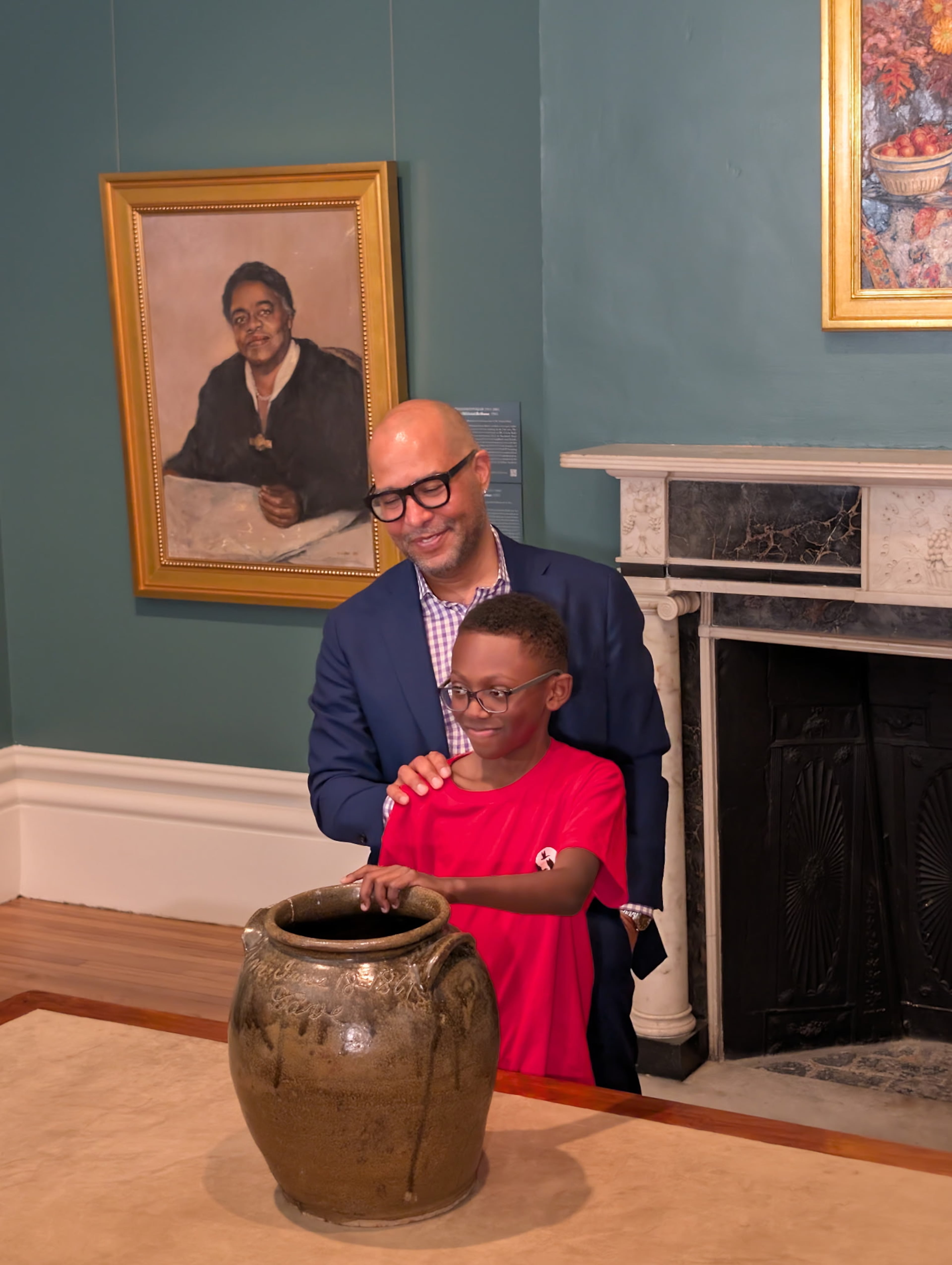 George Fatheree, a family lawyer, stands with David Drake’s heir, sixth-generation grandson Lennox, as he touches a jar made by Drake. (Courtesy)