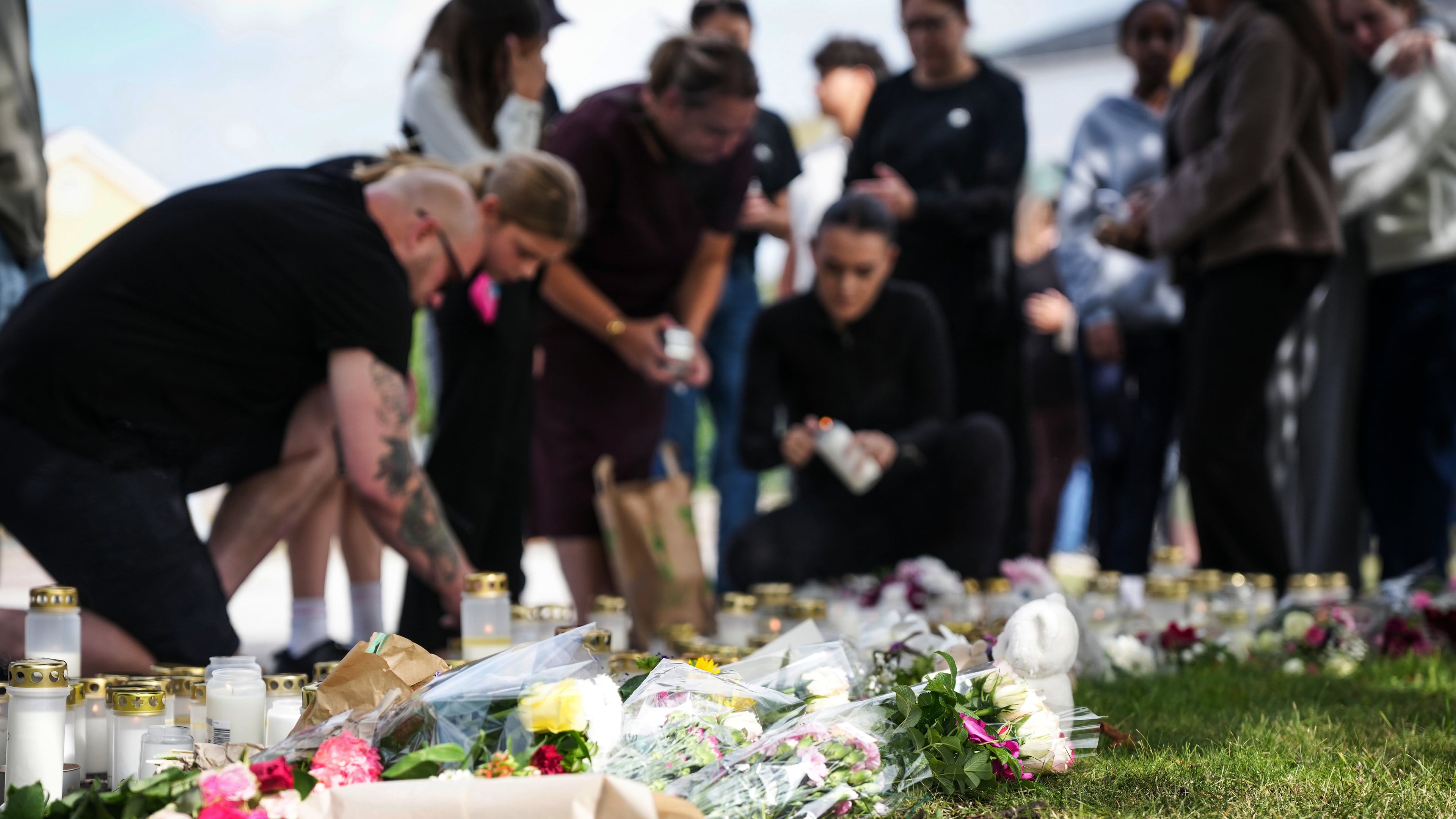 People leave flowers and candles at a makeshift memorial outside a school in Fagersta, Sweden, Saturday Aug. 22, 2026, the day after an 18-year-old with a sword attacked the school killing one person and seriously injuring two others. (Magnus Lejhall/TT via AP)