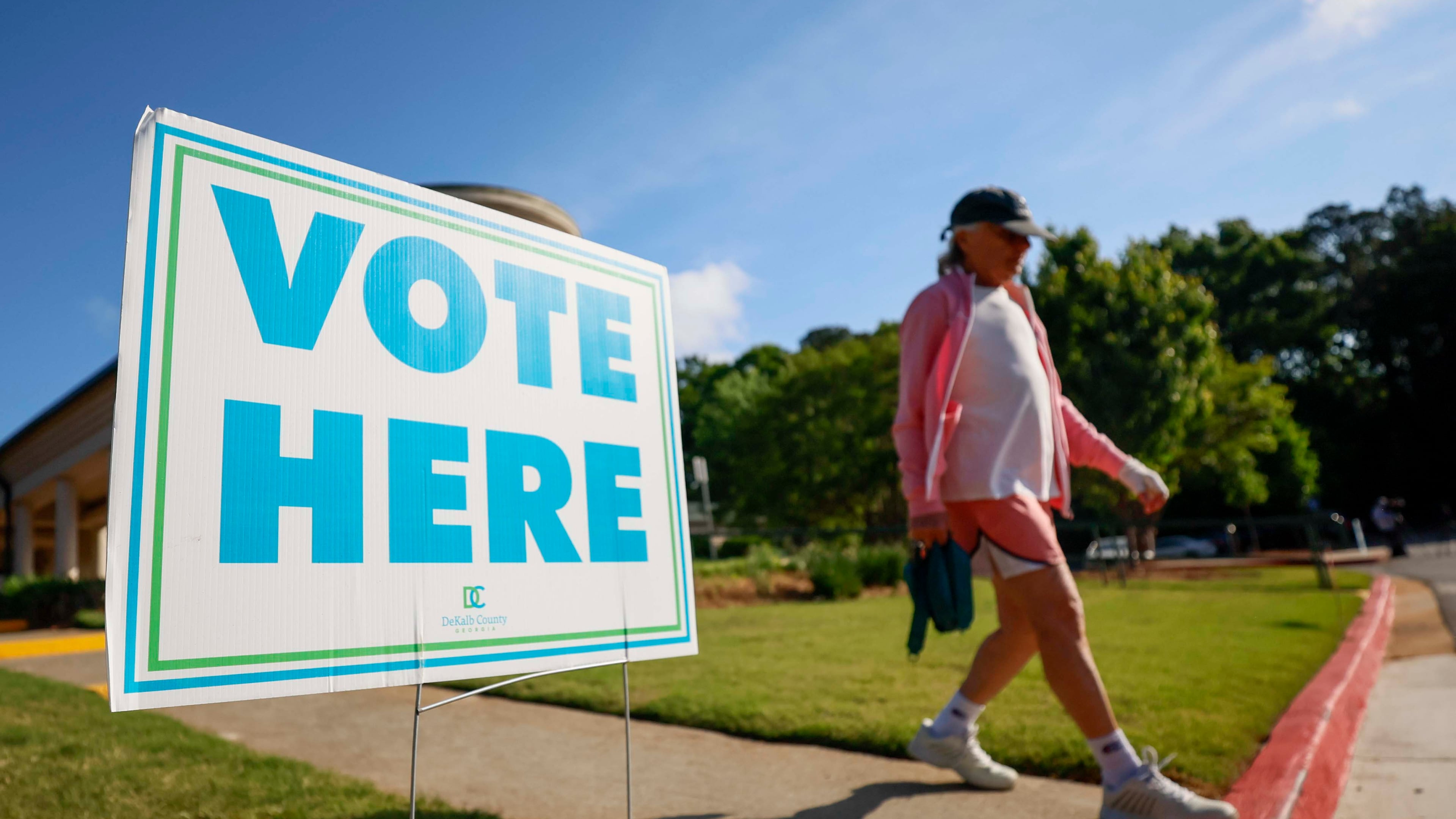 A person walks past a voting sign during the first day of early voting for the primary elections at the Dunwoody Library on Monday. (Miguel Martinez/AJC)