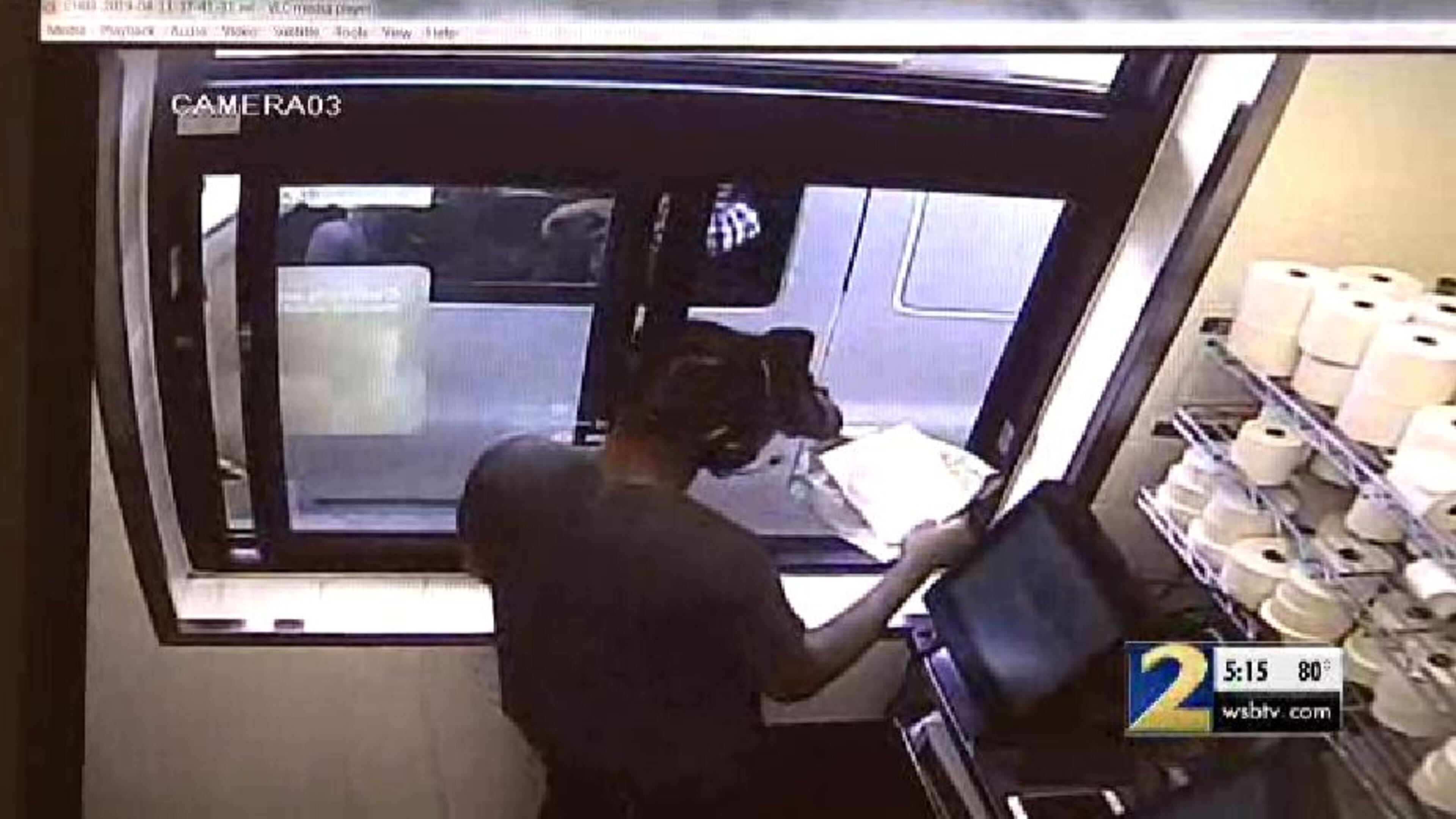 Surveillance footage appears to show a man pull up in a white Chevrolet and pass the cashier a note.