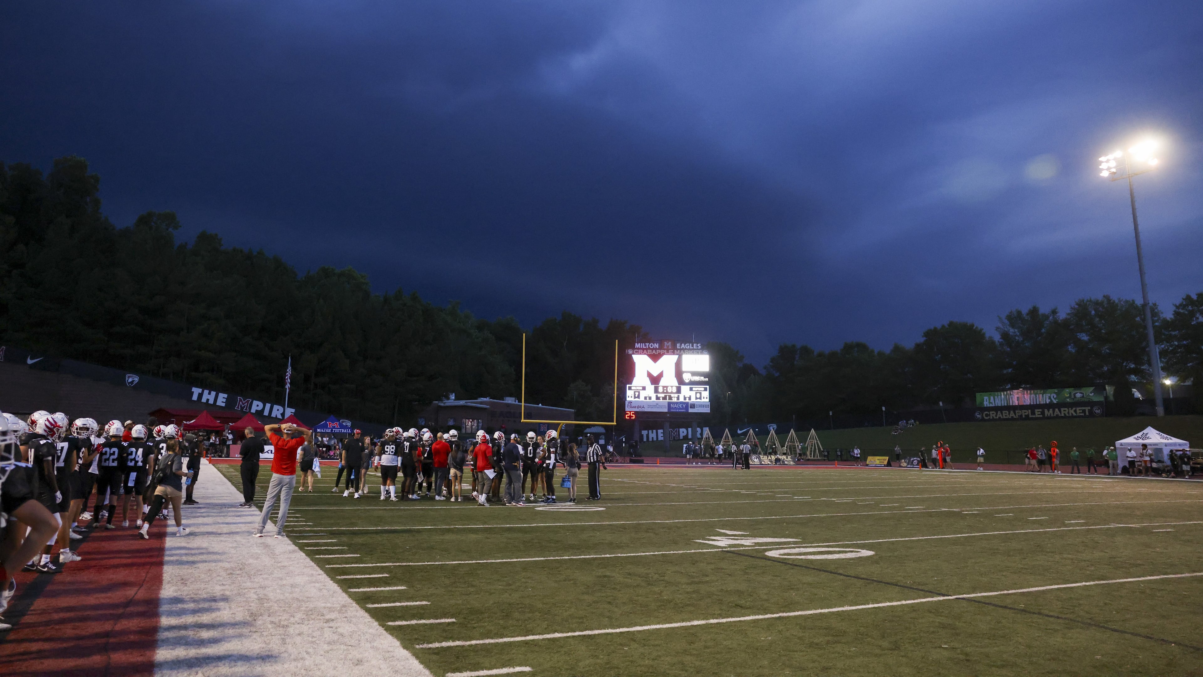 Storm clouds approach the stadium as the Milton defense huddles up against Buford in the first half at Milton High School, Friday, August 16, 2024, in Milton, Ga. (Jason Getz / AJC)
