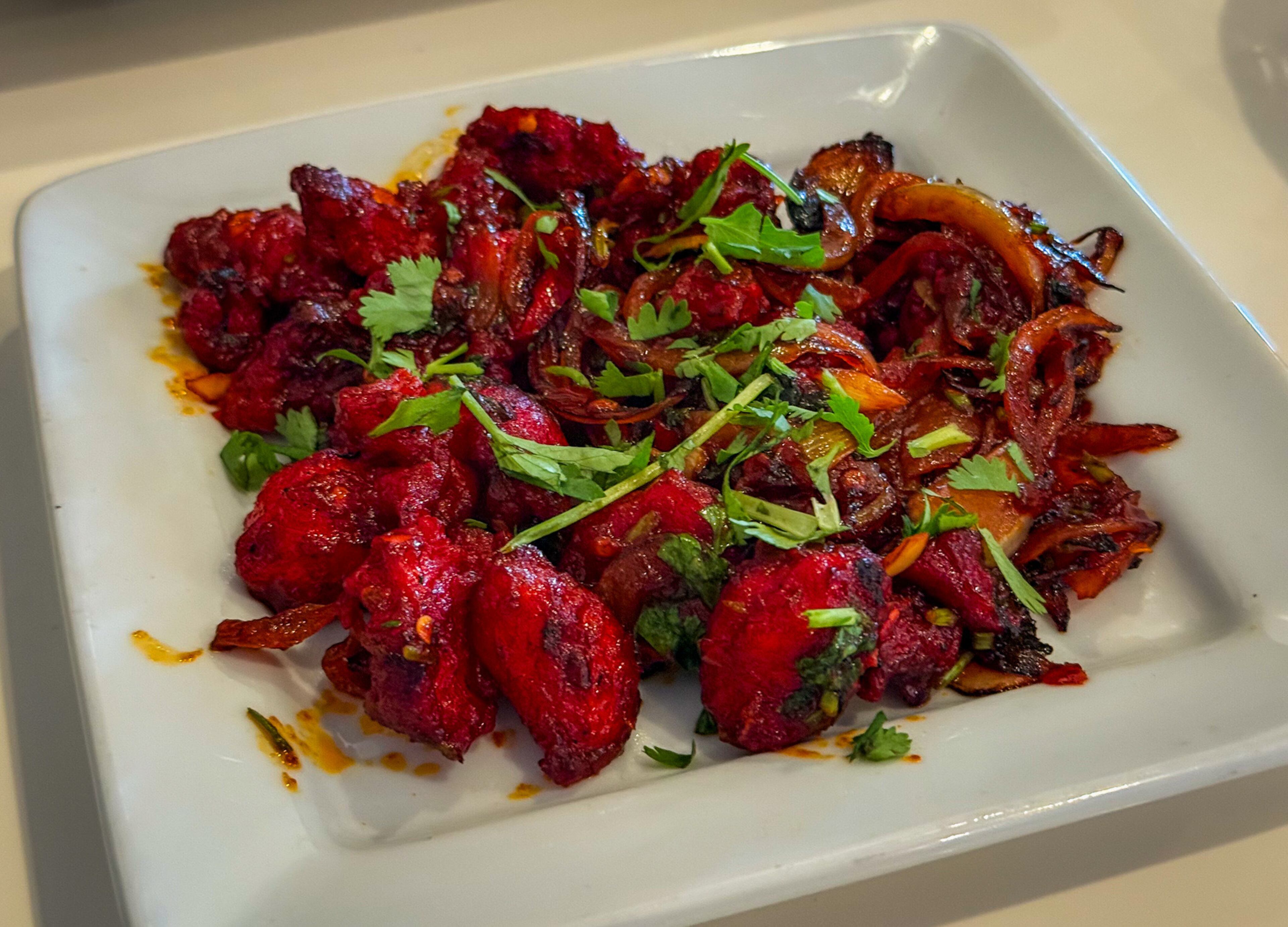 Ruchi's chicken 65 is a classic Indian dish made with fried chicken bits coated in a spicy, deeply flavorful sauce. (Henri Hollis/AJC)