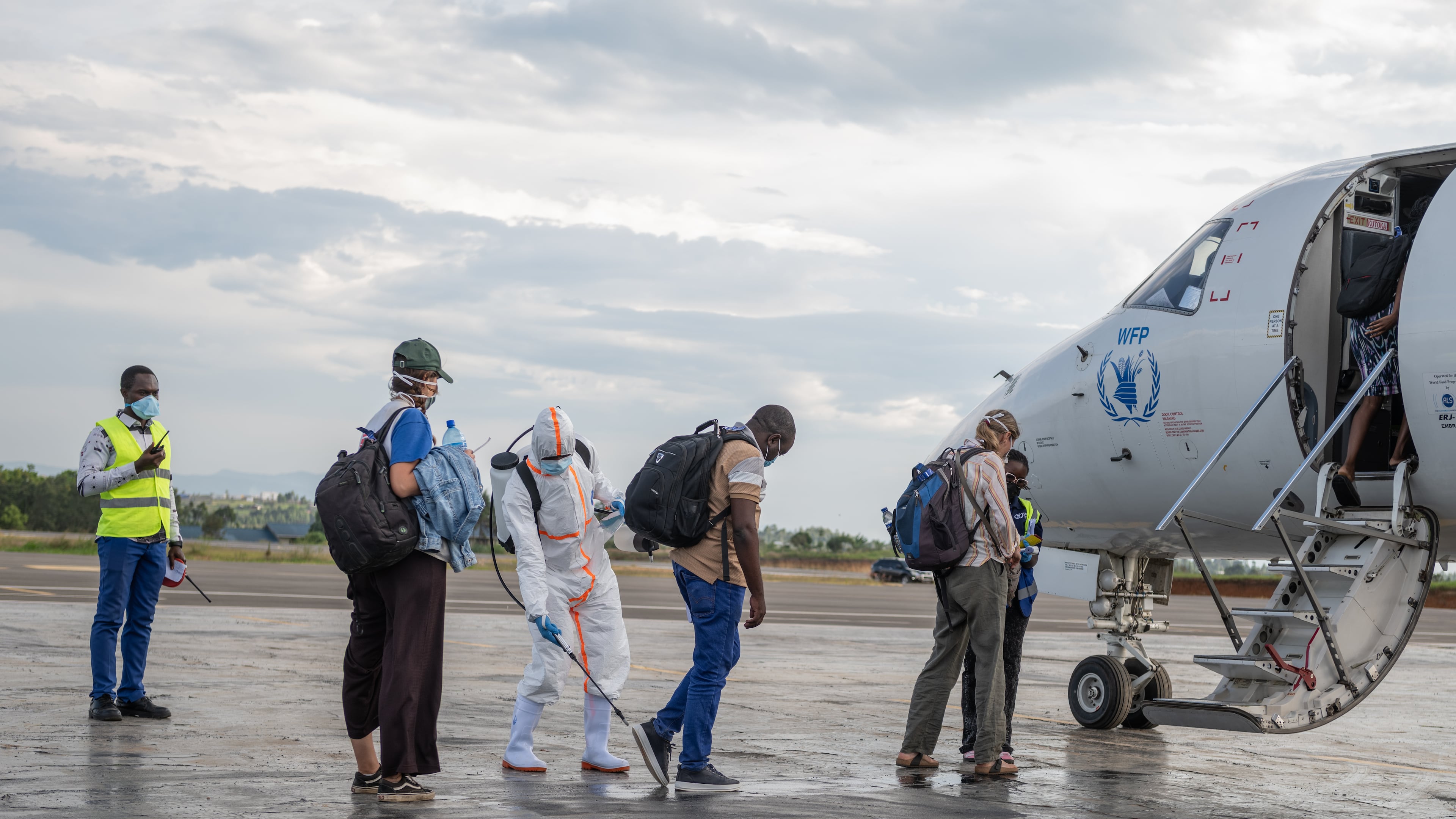A health worker disinfects passengers prior to their boarding of the World Food Programme's (WFP) aircraft following the government's announcement of Bunia National Airport's reopening in Bunia, Congo, Tuesday, June 2, 2026. (AP Photo/Moses Sawasawa)
