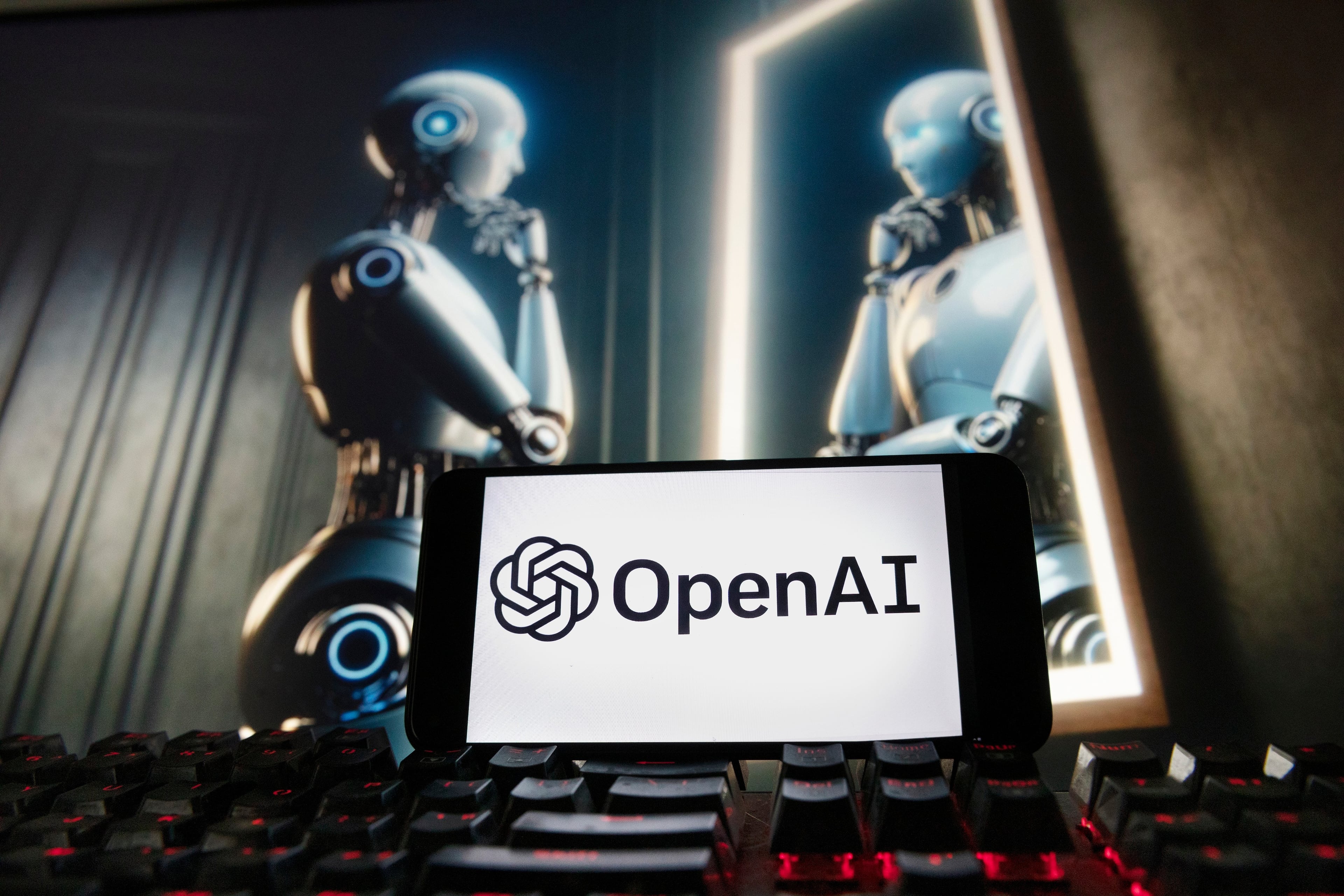 The OpenAI logo is displayed on a cellphone with an image on a computer monitor generated by ChatGPT's Dall-E text-to-image model in this 2023 photograph. (Michael Dwyer/AP)