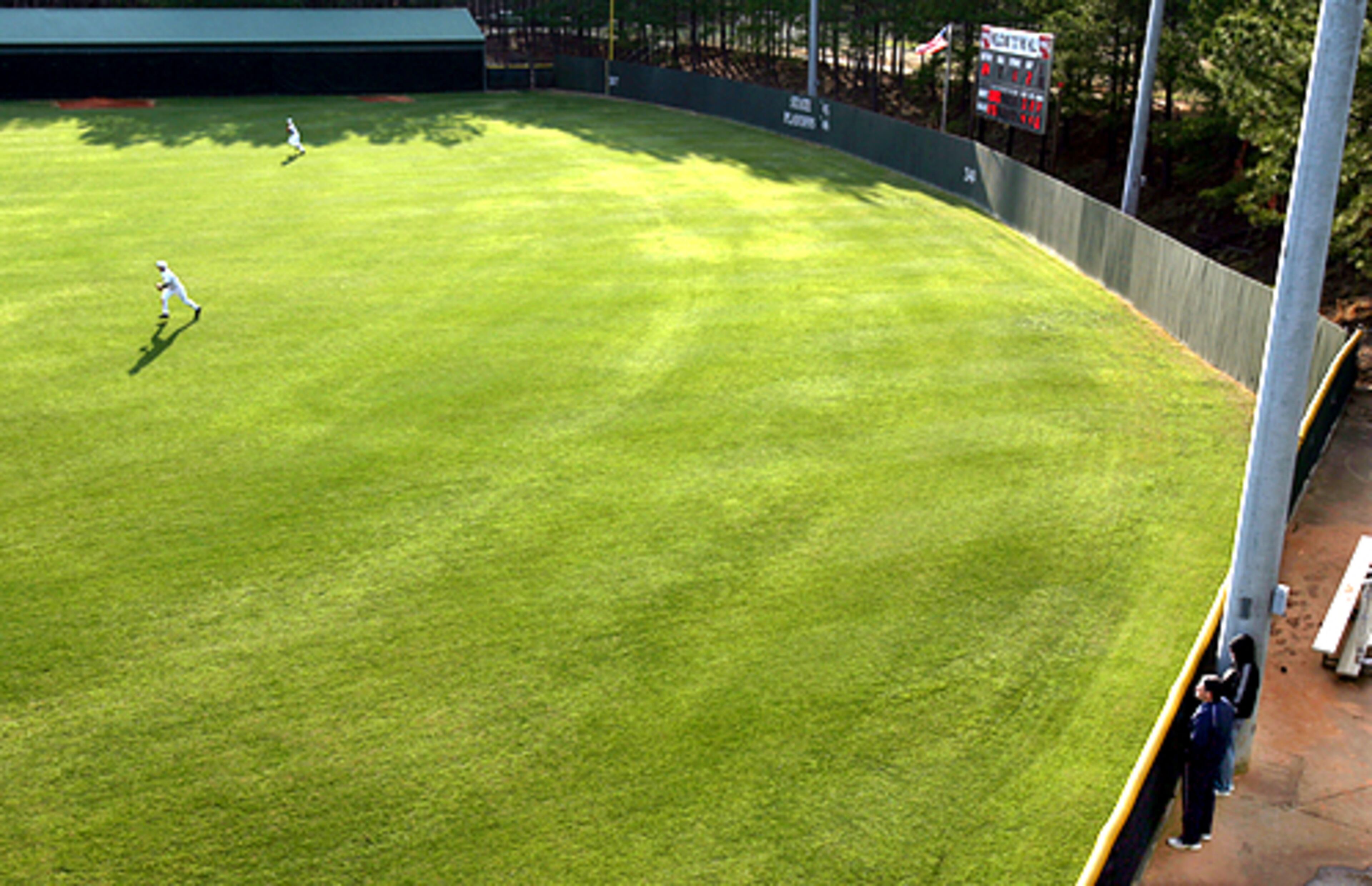 Collins Hill center fielder Michael Adams and left fielder Curtis Guest (top left) move on a hit ball by Duluth as fans peek in over the fence in Suwanee. Collins Hill coach Paul Pierce said the most unique part of the stadium is the split level outfield.