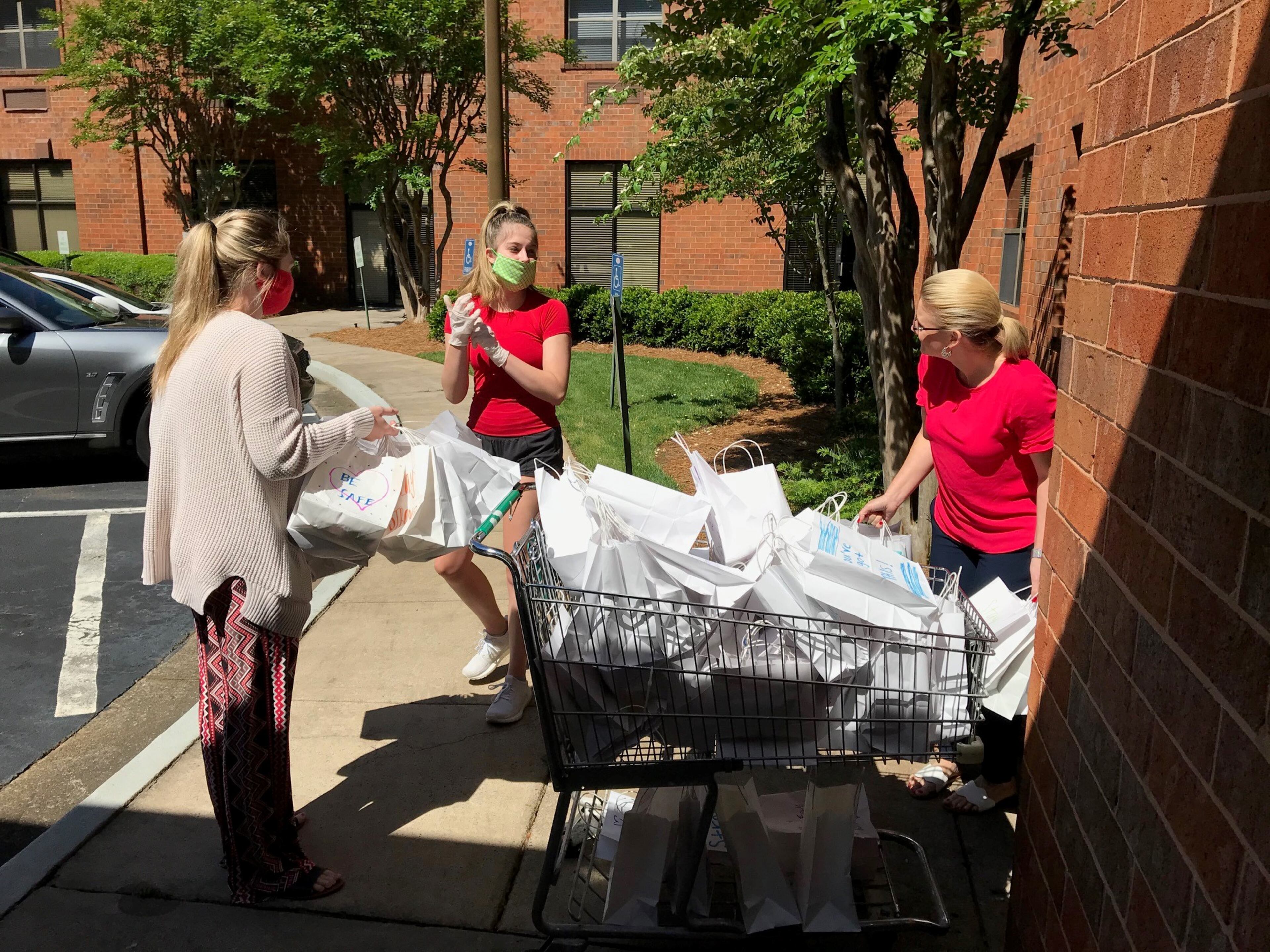 Avery Pursell (center) delivers gifts bags to Rita Malone (right), assistant executive director at Mount Vernon Towers Condominiums, with assistance from staffer Taylor Williams (left.) Pursell and her colleagues collected 300 books of large-print crossword puzzles and other amusements to distribute to the residents at the senior living center. BO EMERSON/BEMERSON@AJC.COM