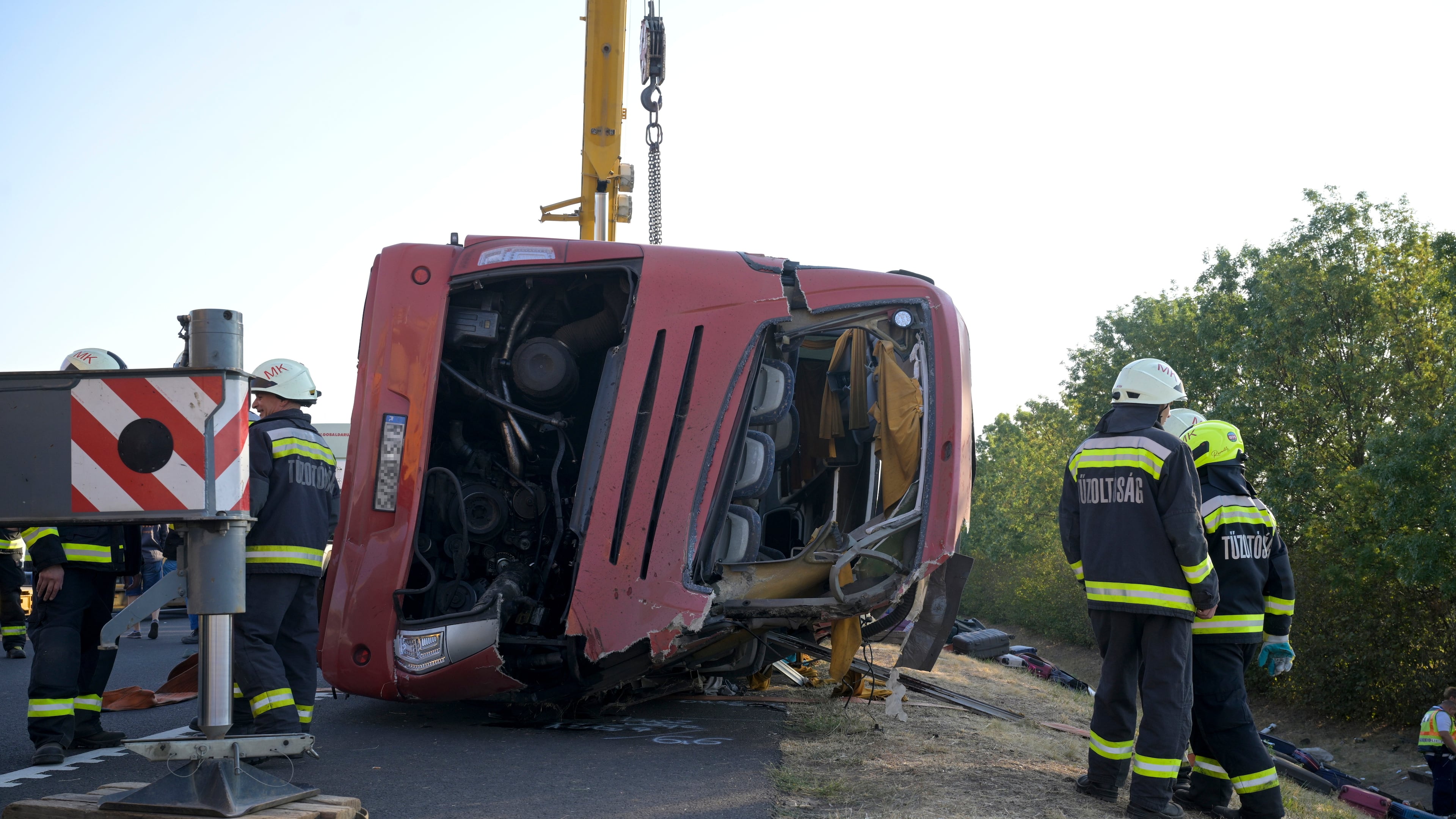 Emergency services attend the scene after a passenger bus went off the road and overturned in a ditch along a highway between Mezokeresztes and Mezonagymihaly in Hungary, Sunday, Aug. 16, 2026. (Zoltan Mathe/MTI via AP)