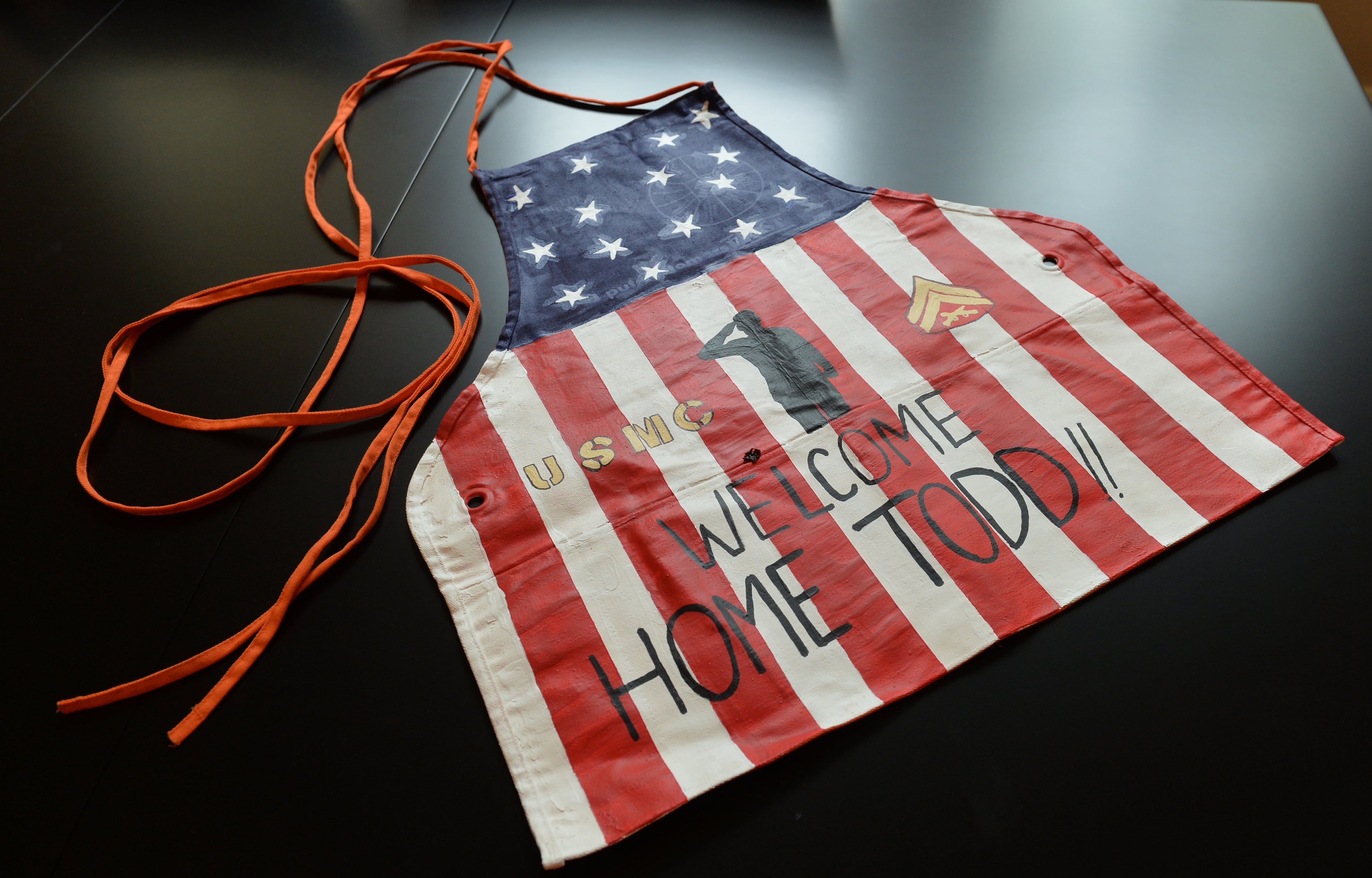 Custom painted Home Depot apron presented Marine Corporal Todd Love during the unveiling ceremony of his new home. Love lost both legs and his left arm to an IED blast in 2010 while on patrol in Afghanistan. Home Depot and other corporate sponsors, in conjunction with the Stephen Siller Tunnel to Towers Foundation and the Gary Sinise Foundation, built the home as part of the Building for America's Bravest program. The 3700 feet 4 bed 3 bath "smart home" features an open floor plan, automatic toilets, oversize shower with roll in access, motorized doors, drop down kitchen cabinets that make it easier for Love to reach stored items, a cook top that lowers and a complete security system just to name a few features that will make it easier for Love to take care of his needs. BRANT SANDERLIN /BSANDERLIN@AJC.COM .