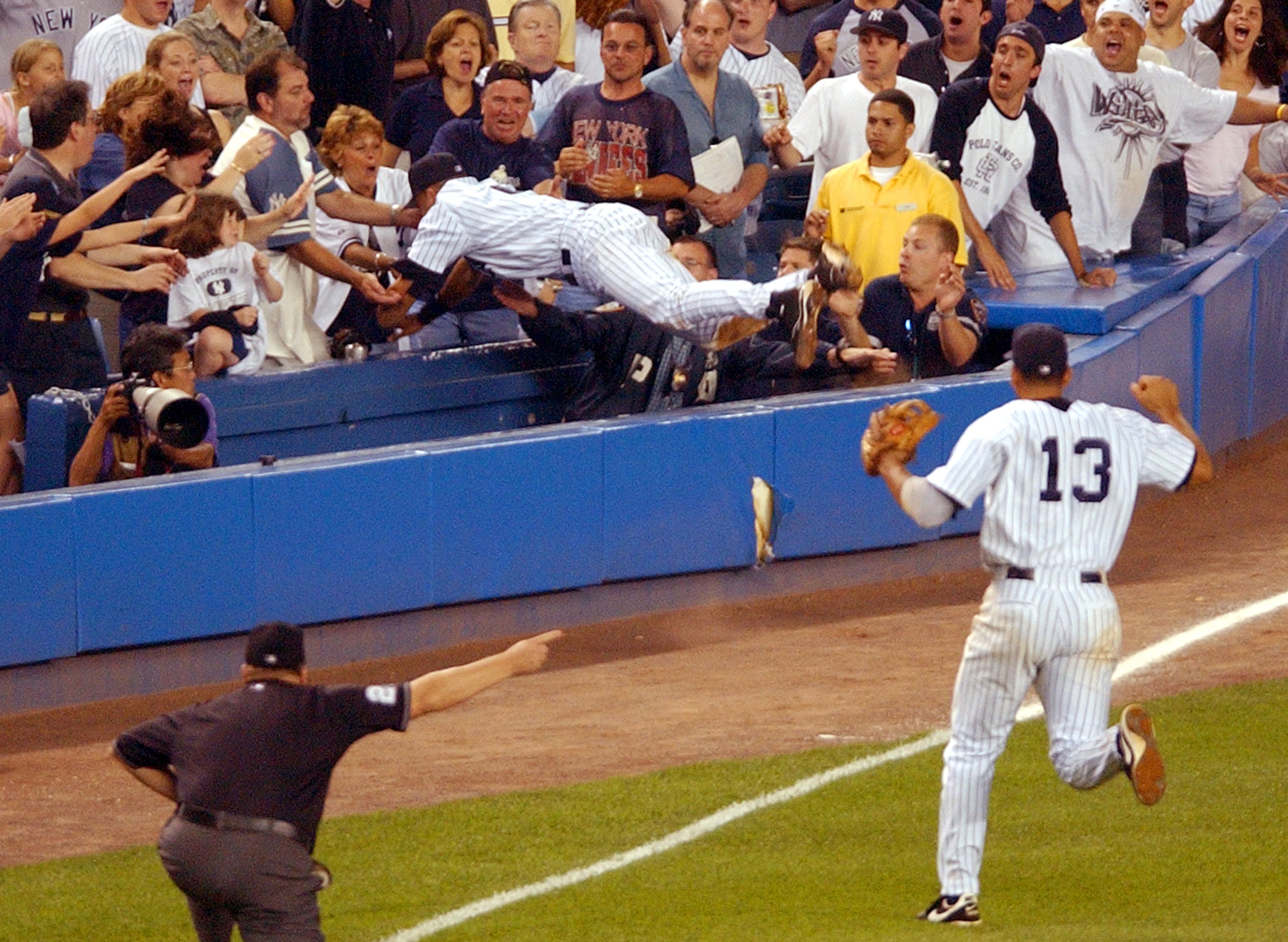 FILE - In this July 1, 2004, file photo, New York Yankees shortstop Derek Jeter, top, dives into the stands to catch a fly ball in the 12th inning of a baseball game against the Boston Red Sox at New York's Yankee Stadium. (AP Photo/Frank Franklin II, File)