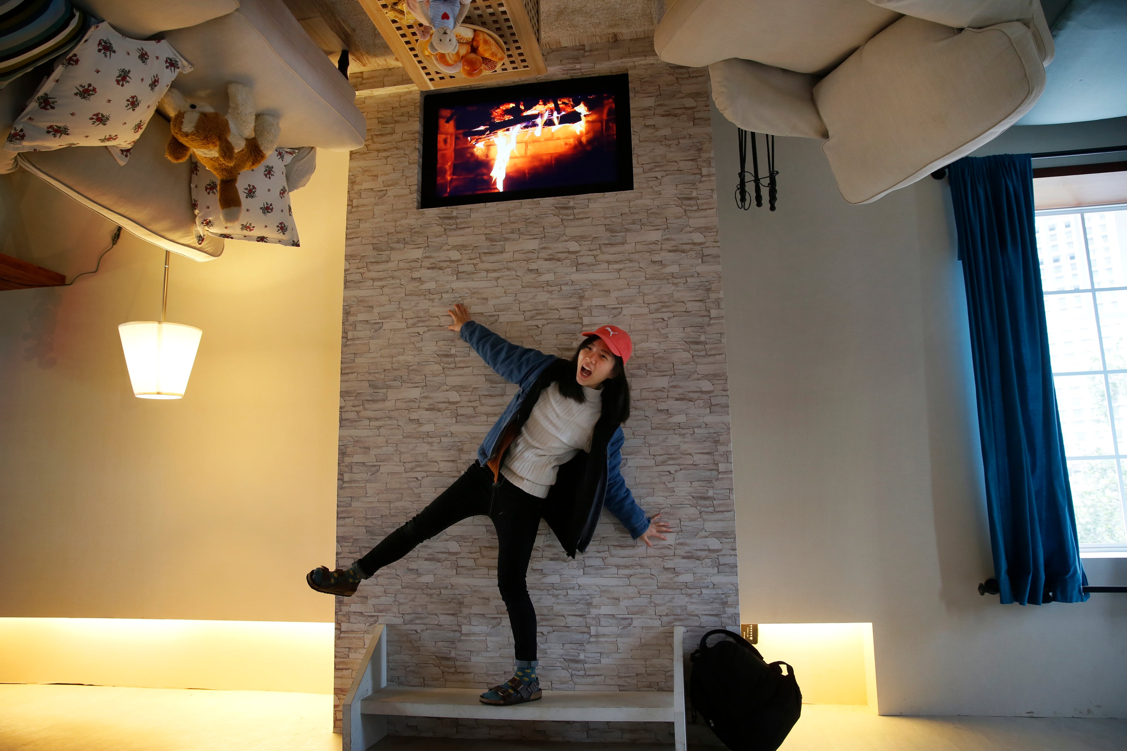 The appliances are real, with working lights throughout. The overhead fireplace, though, is an LCD screen of a cozy fire. A visitor poses inside an upside-down house created by a group of Taiwanese architects at the Huashan Creative Park in Taipei, Taiwan, Tuesday, Feb. 23, 2016. (AP Photo/Wally Santana)