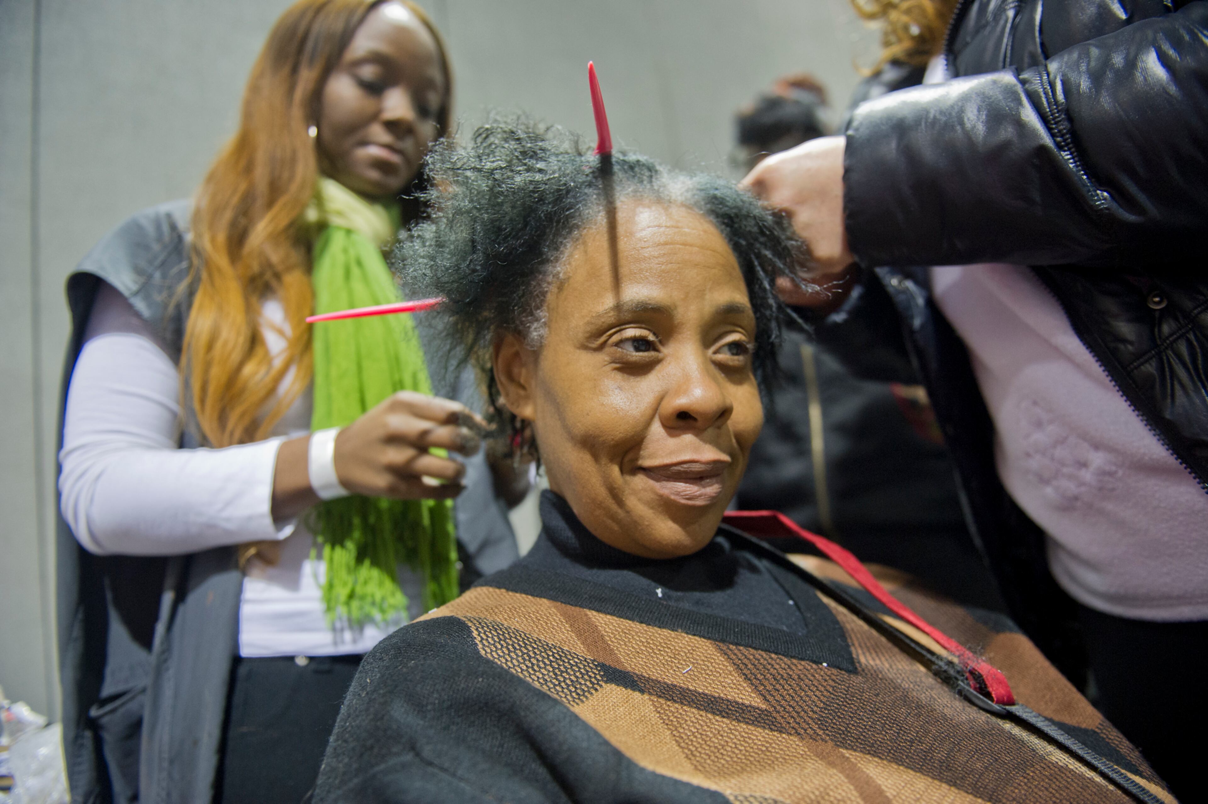 Santina Story (center) gets a haircut from Kirstin Stokes during the Hosea Feed the Hungry and Homeless annual Thanksgiving meal at the Georgia World Congress Center in Atlanta on Nov. 28, 2013.